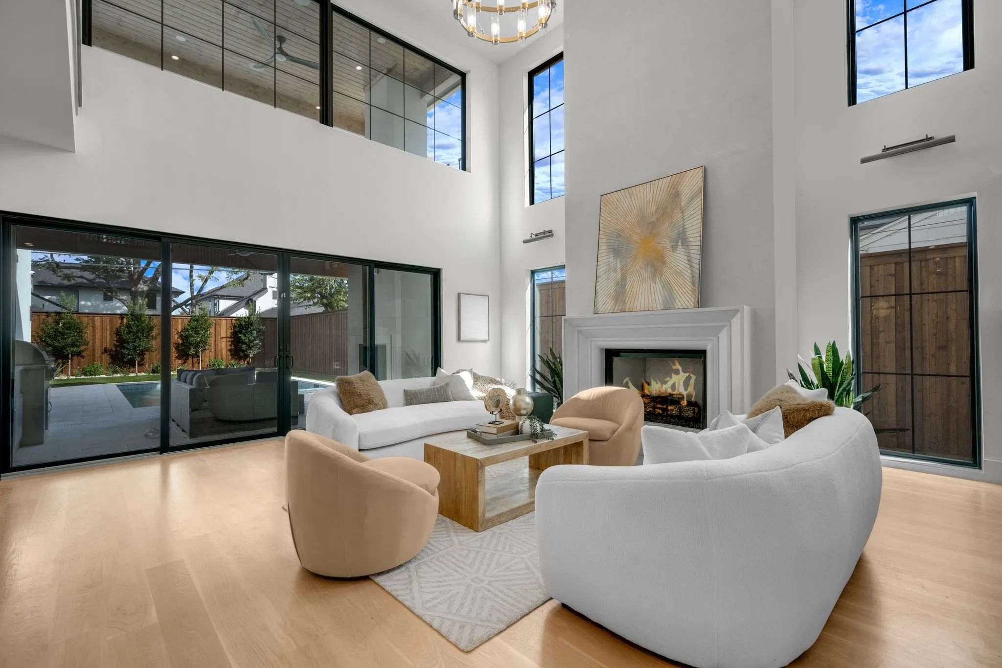 High ceilings with upper-level windows, a built-in fireplace with a mantel, expansive sliding glass doors, and light wood-finish flooring