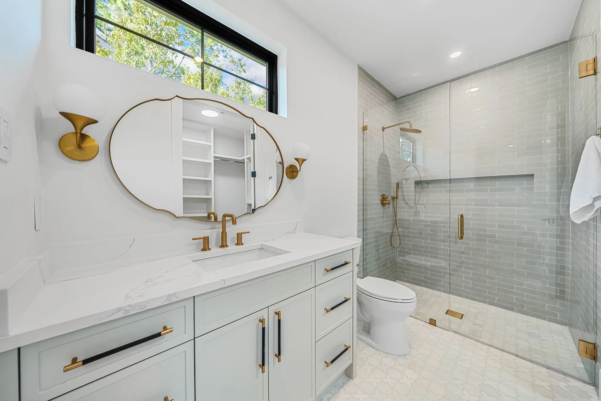 White vanity with gold-tone hardware and a countertop with integrated sink