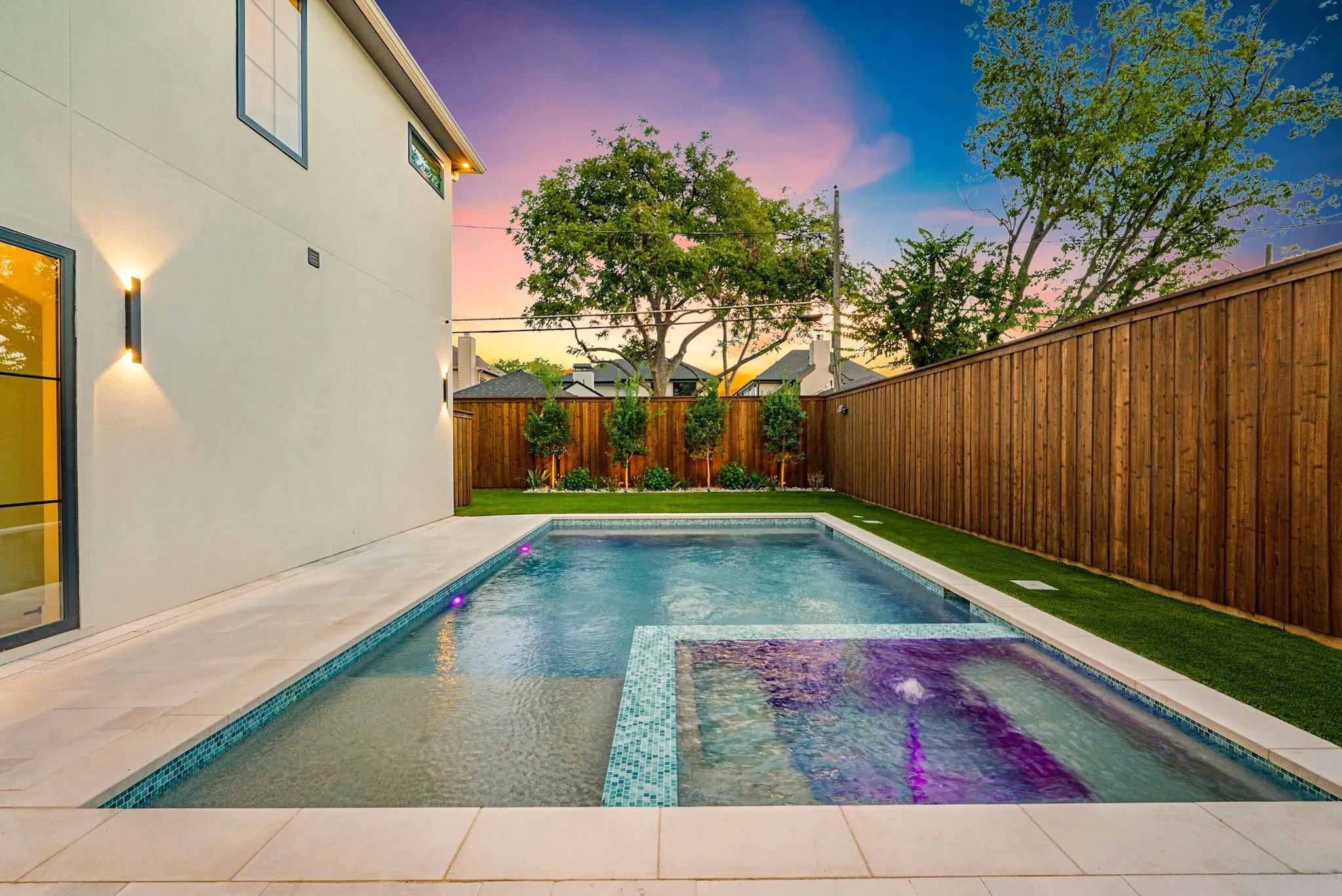 Rectangular swimming pool with integrated spa, bordered by a light-toned paved deck