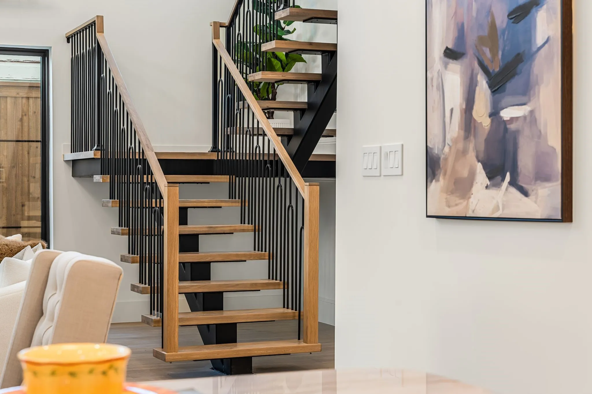 Open-tread staircase with wood finish treads and black metal balusters
