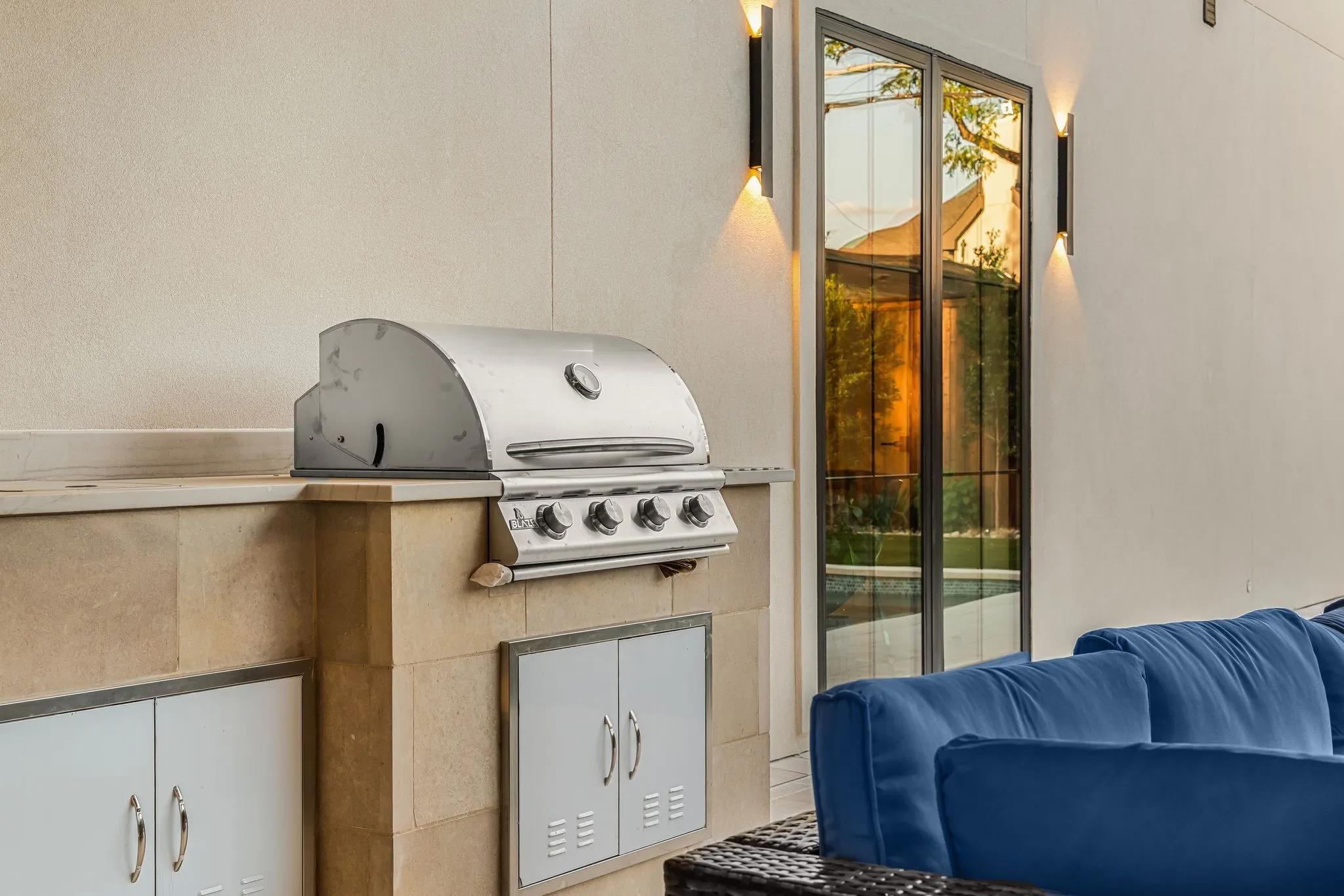 Outdoor kitchen featuring a built-in stainless steel grill, stone-clad cabinetry, and a countertop prep area
