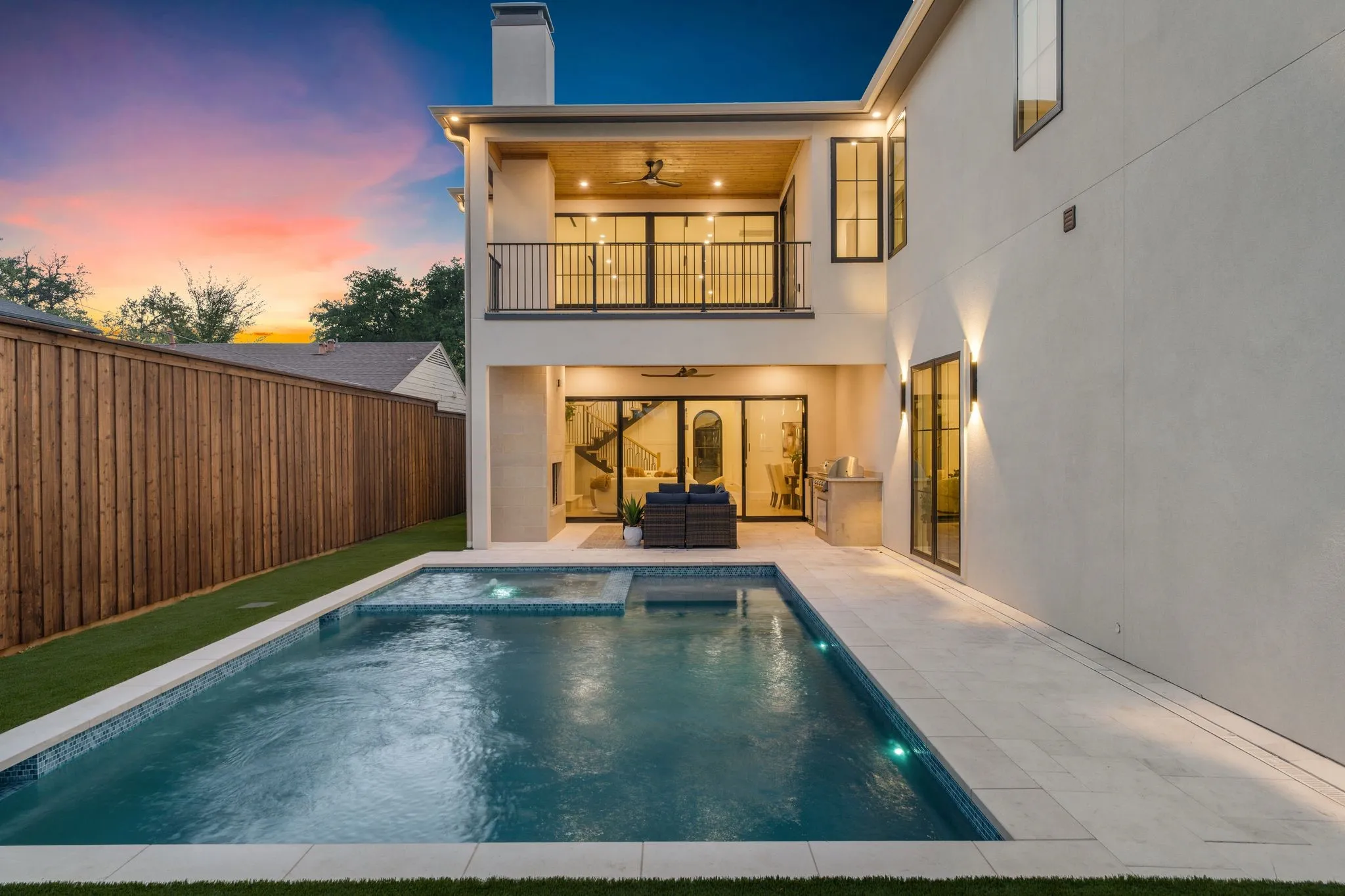 Outdoor living space featuring a swimming pool, integrated spa, covered patio, second-story balcony, and outdoor kitchen