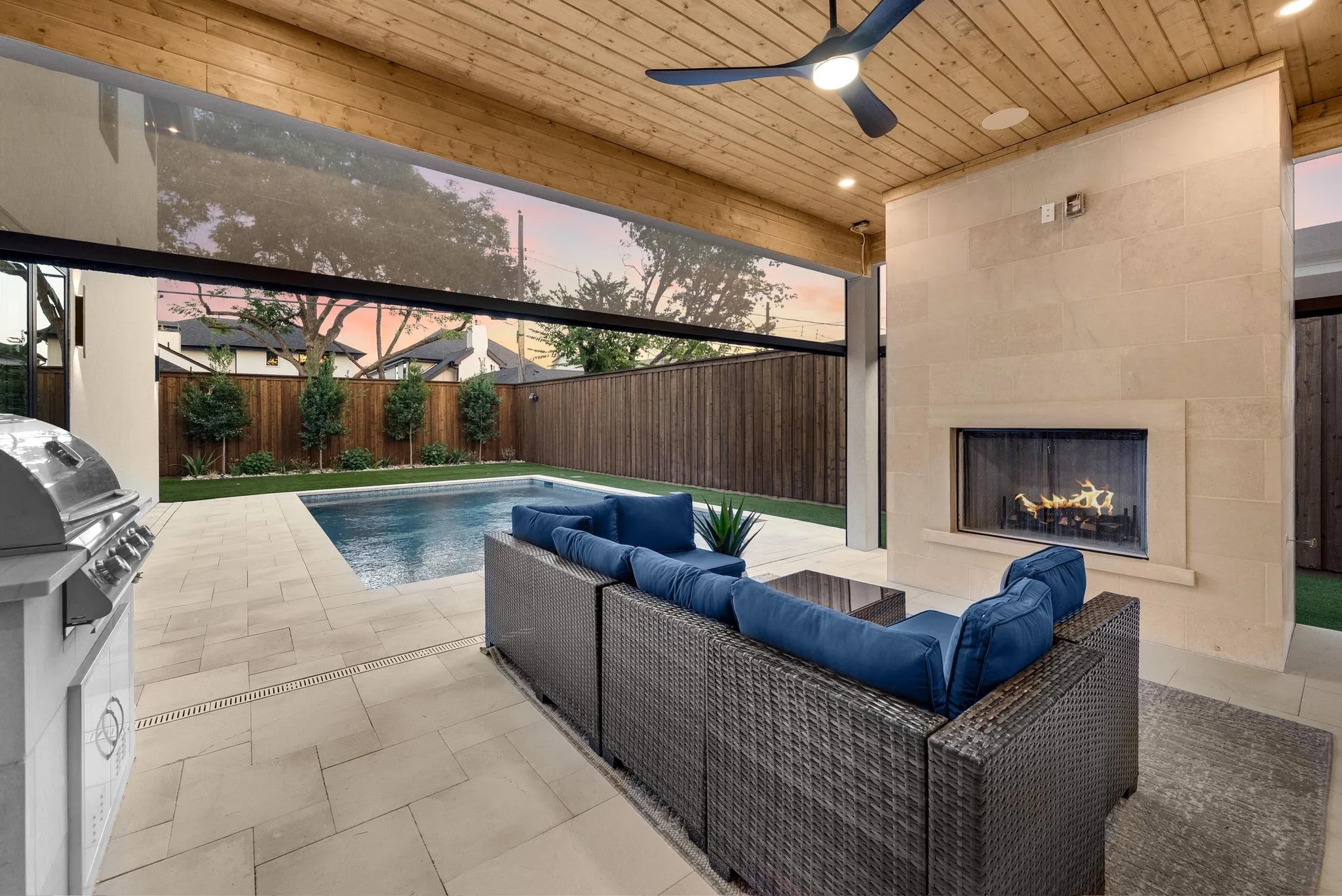 Outdoor living area featuring a built-in fireplace, swimming pool, and wood-finish ceiling with a ceiling fan