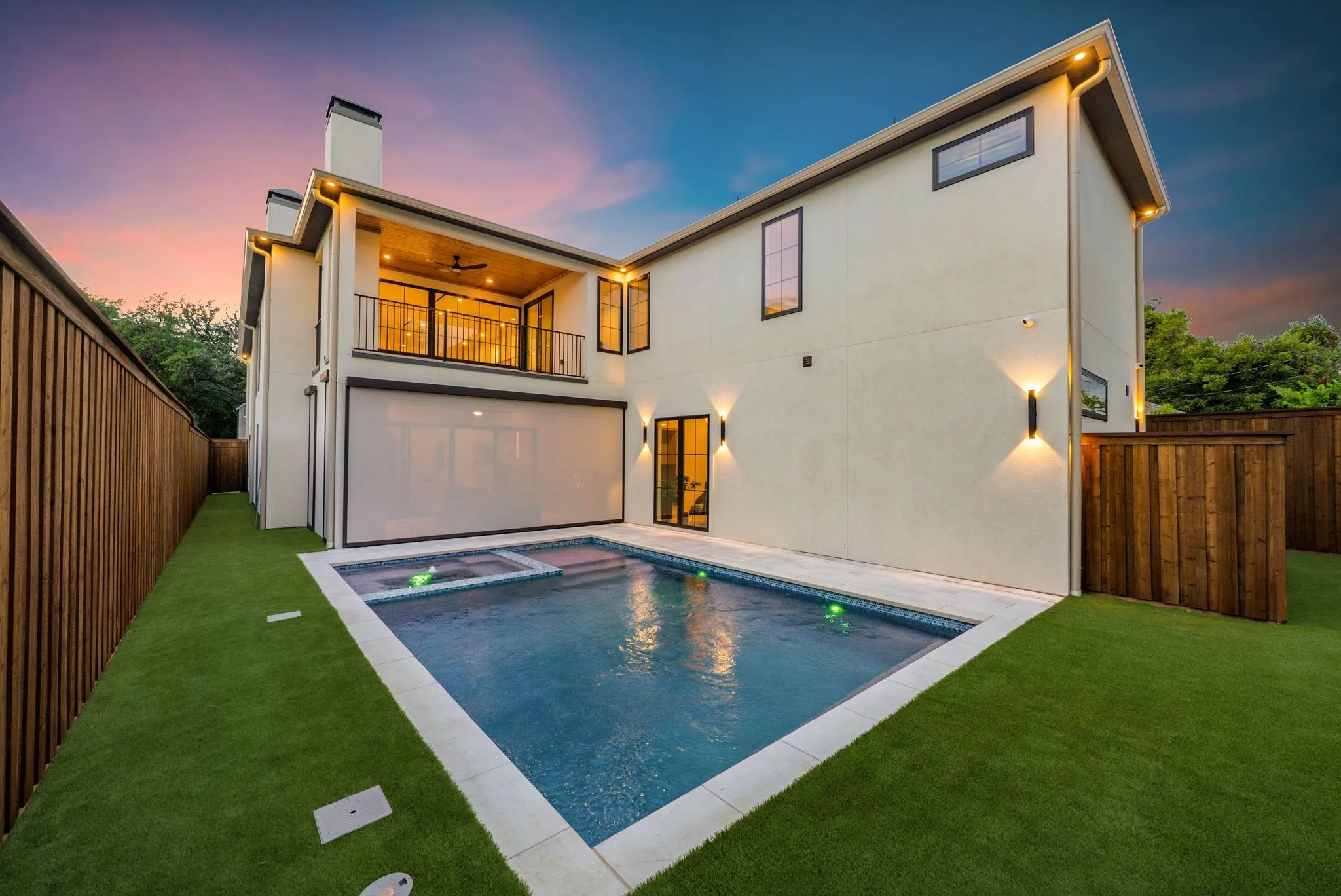 Rectangular swimming pool with integrated spa, bordered by artificial turf