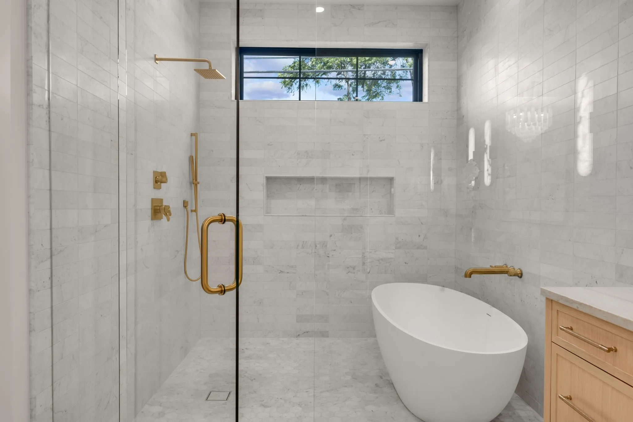 Walk-in shower with clear glass enclosure and gold-finish fixtures
