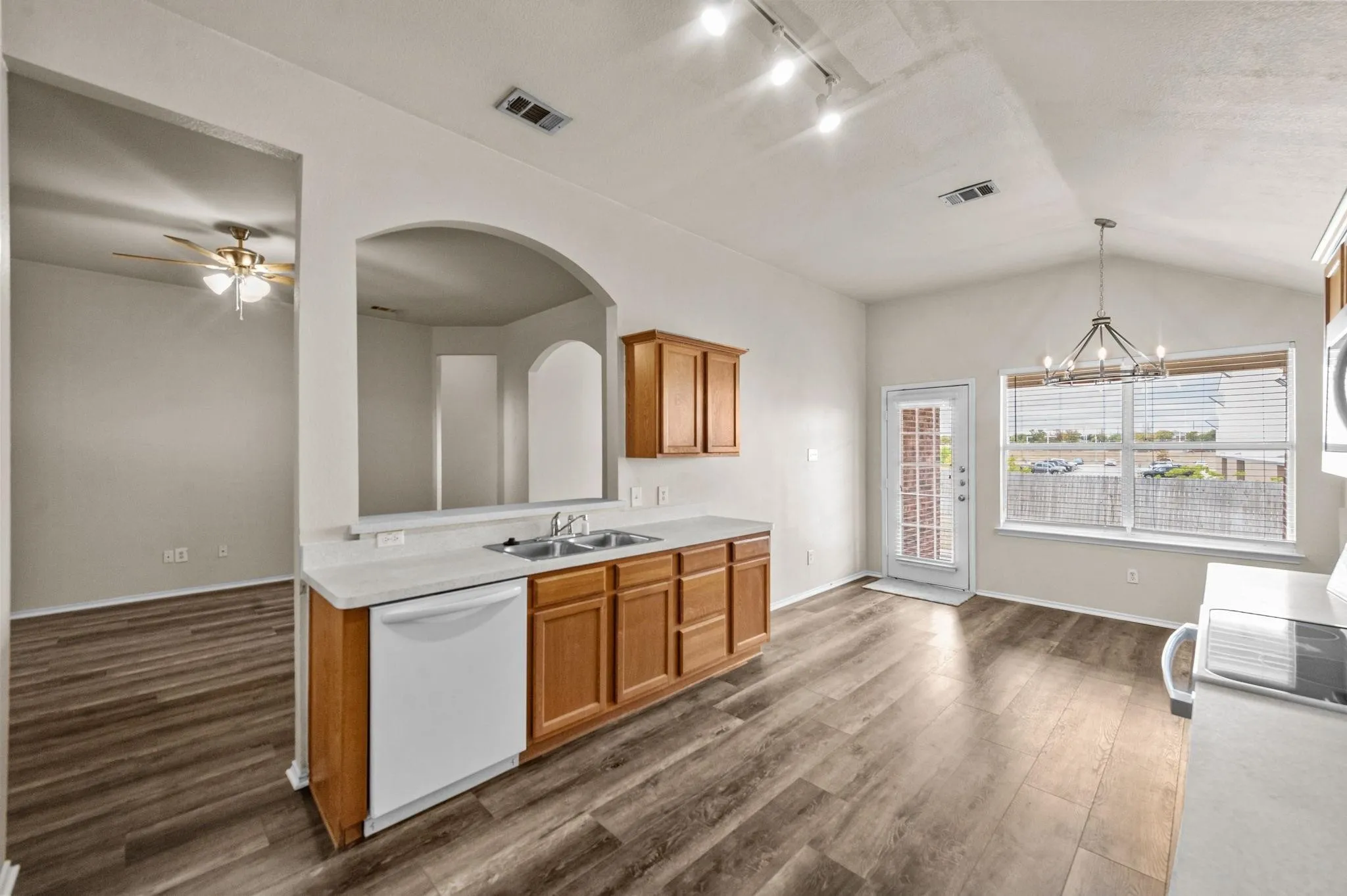 Kitchen featuring wood-finish flooring, white countertops, wood cabinetry, built-in dishwasher, and a chandelier-style light fixture