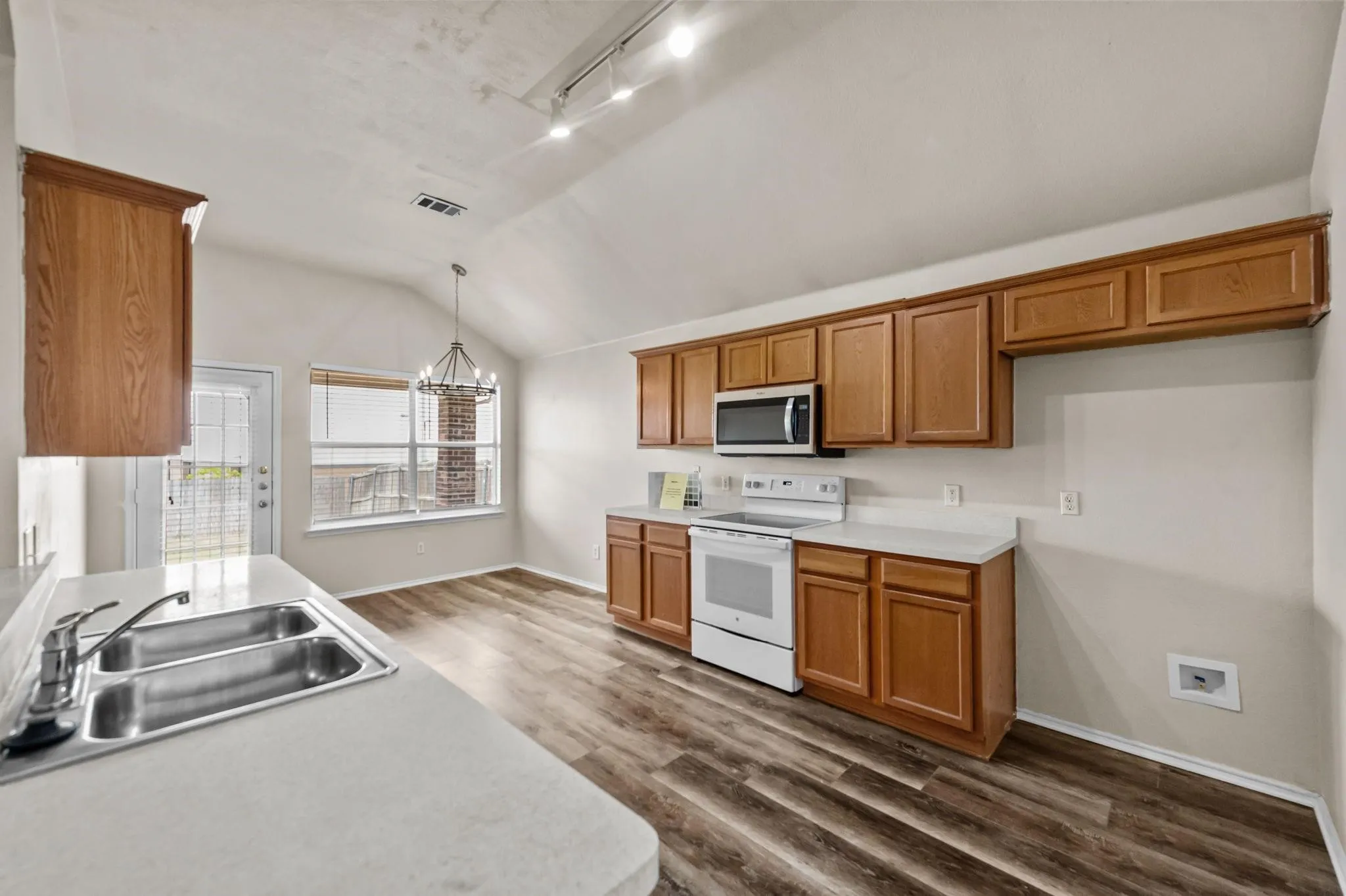 Kitchen featuring wood-finish flooring, vaulted ceiling, and track lighting