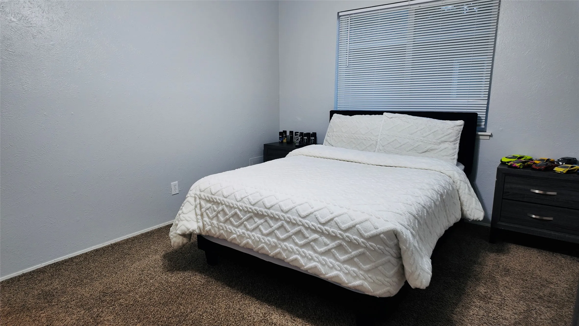 Neutral wall color with textured finish, window with horizontal blinds, and carpeted flooring