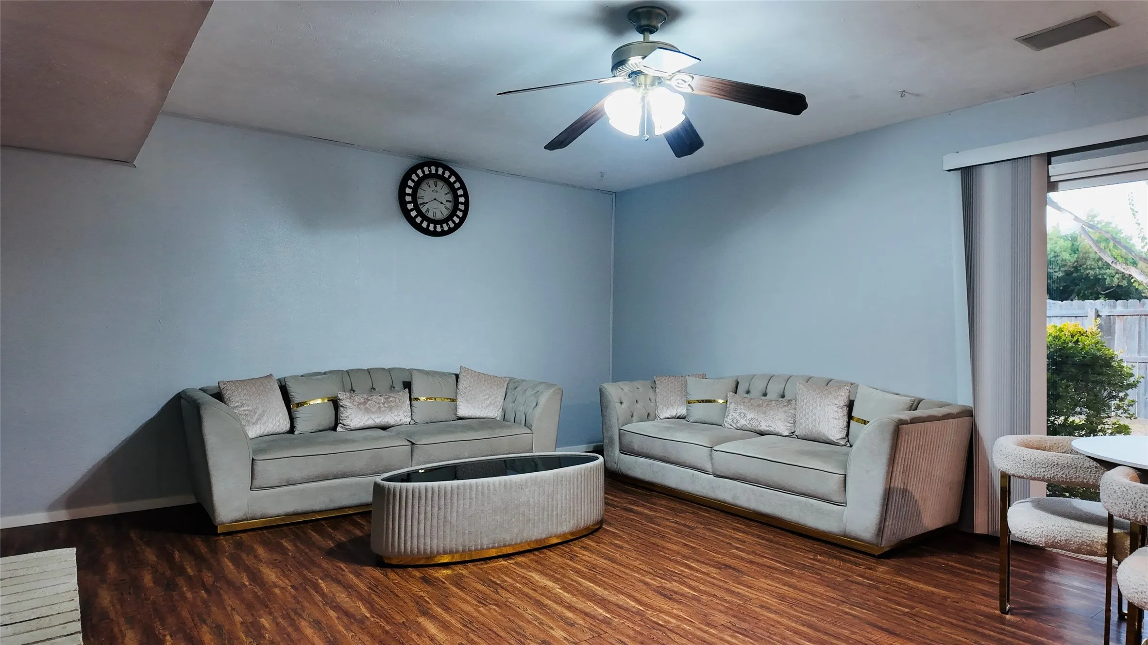 Wood-finish flooring throughout, ceiling fan with integrated lighting, and a sliding glass door providing access to the exterior