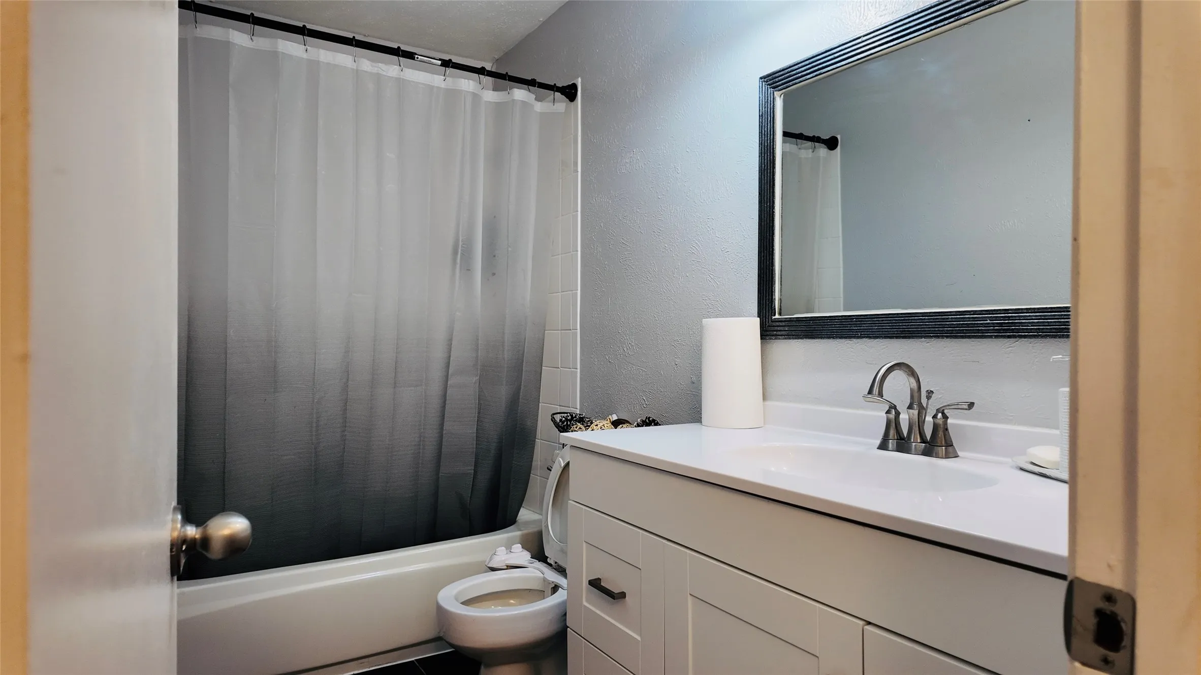 White vanity with integrated sink, brushed nickel faucet, and framed mirror