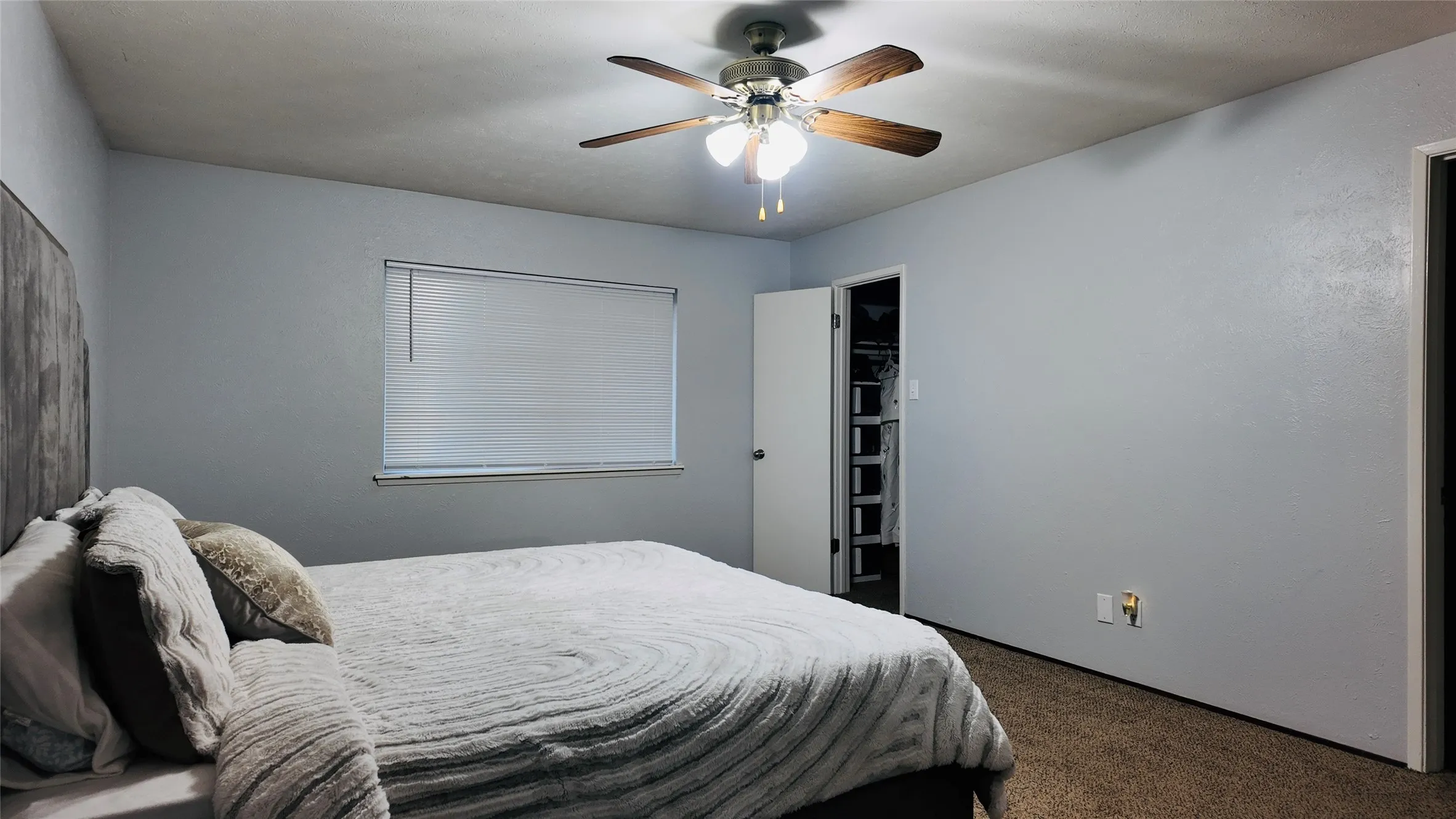 Neutral-toned walls with a ceiling fan light fixture and window with blinds