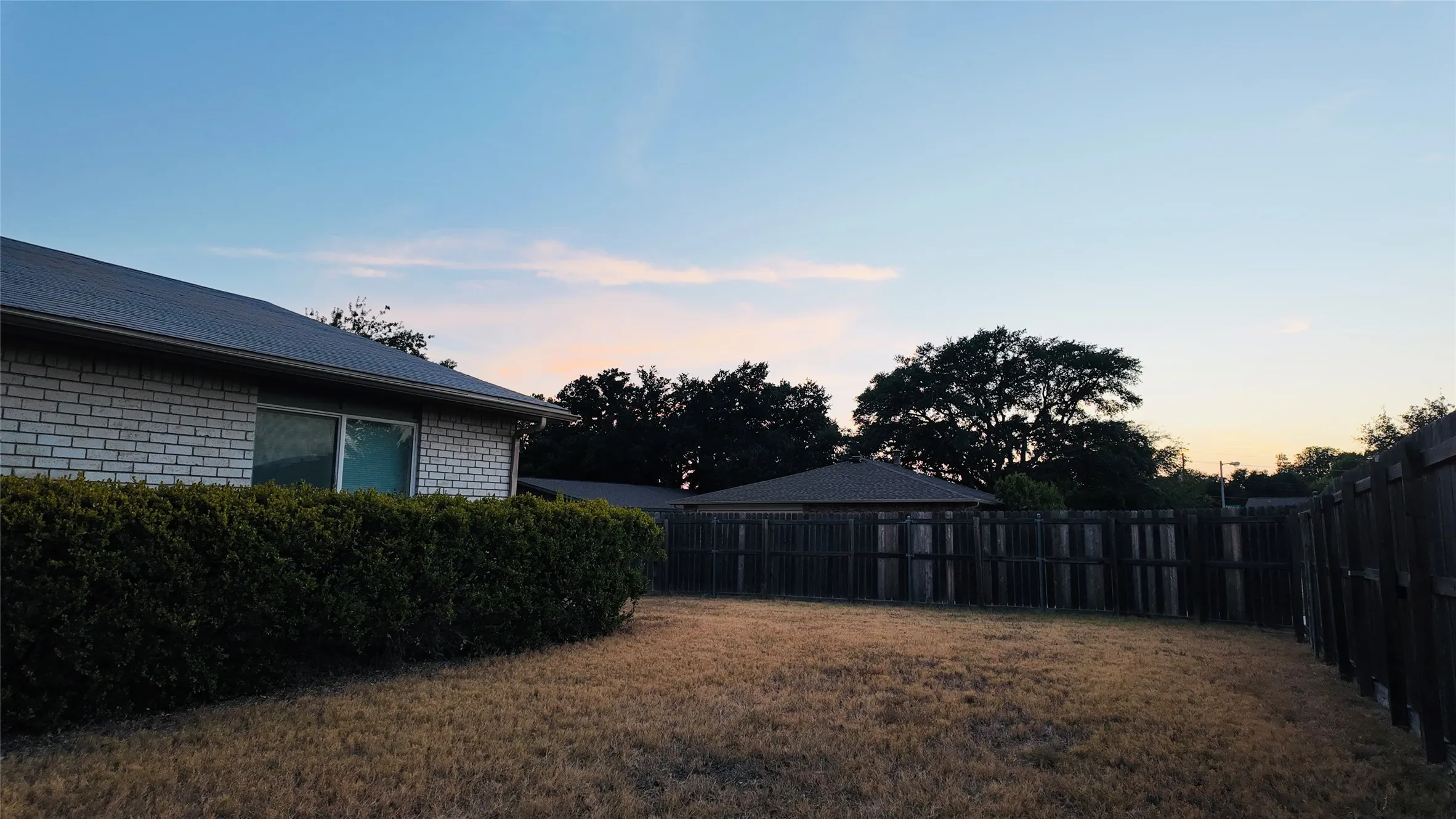 Brick exterior with a dark roof and a perimeter hedge