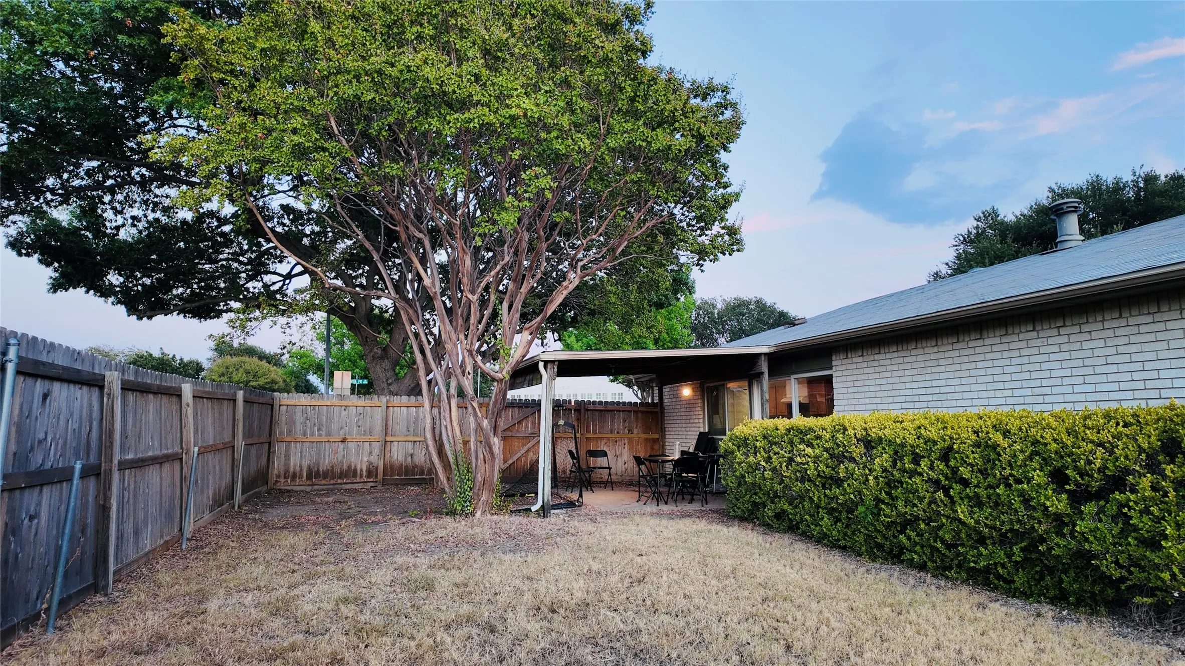Private backyard with wood fencing, mature trees, and a covered patio