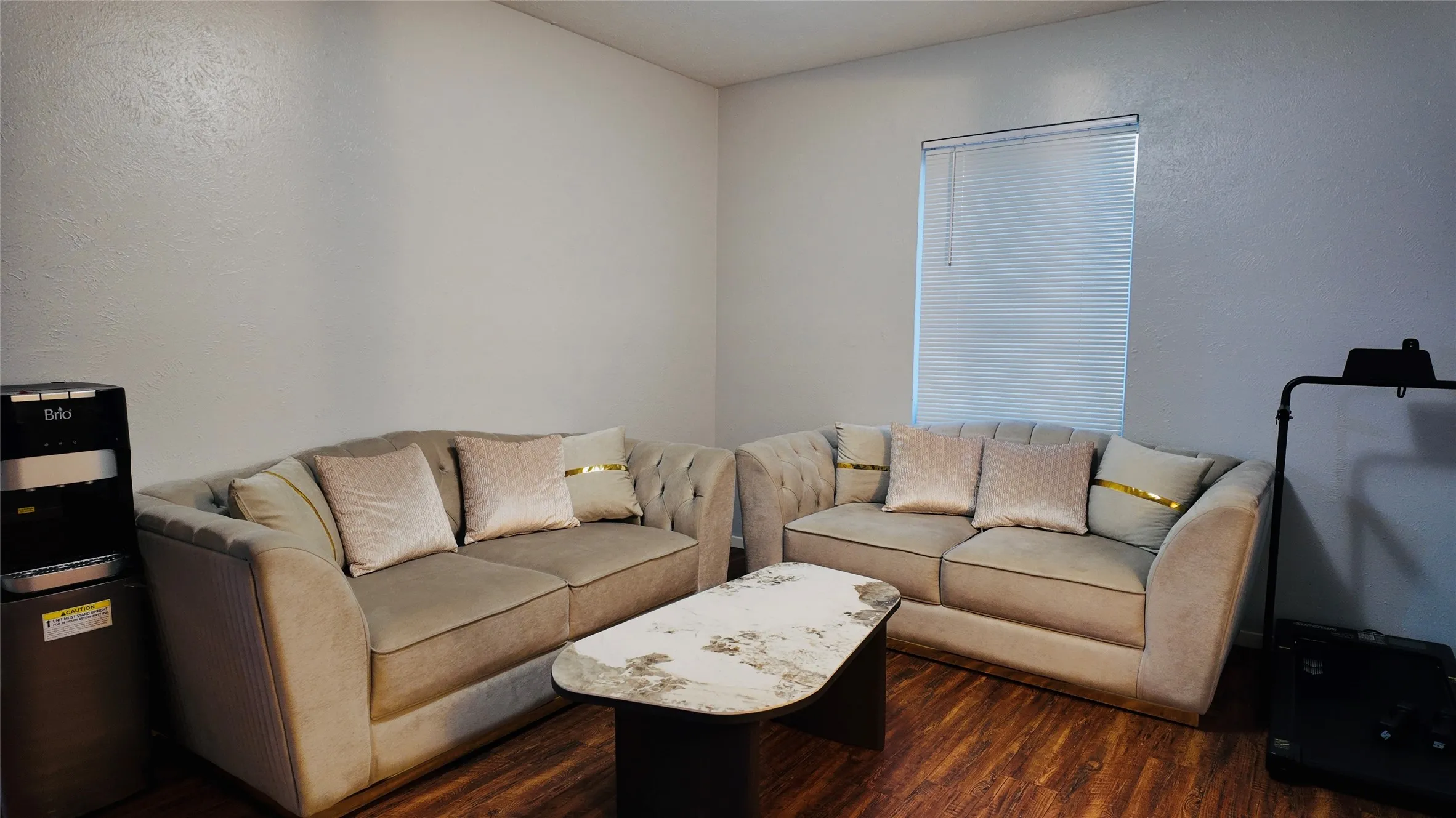 Wood-finish flooring, white walls, and a window with horizontal blinds