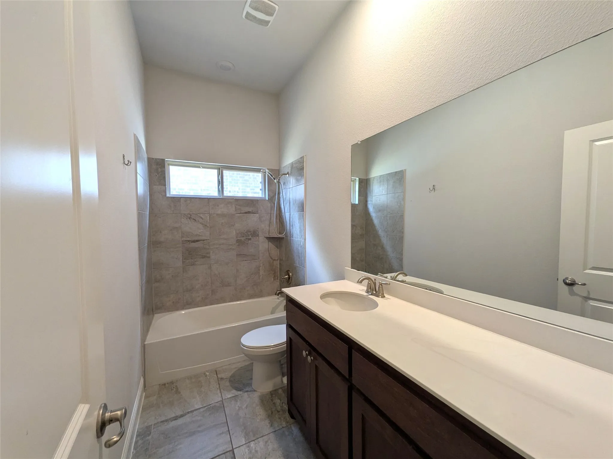 Full bathroom with a tub/shower combination, vanity with integrated sink, rectangular mirror, and tiled flooring
