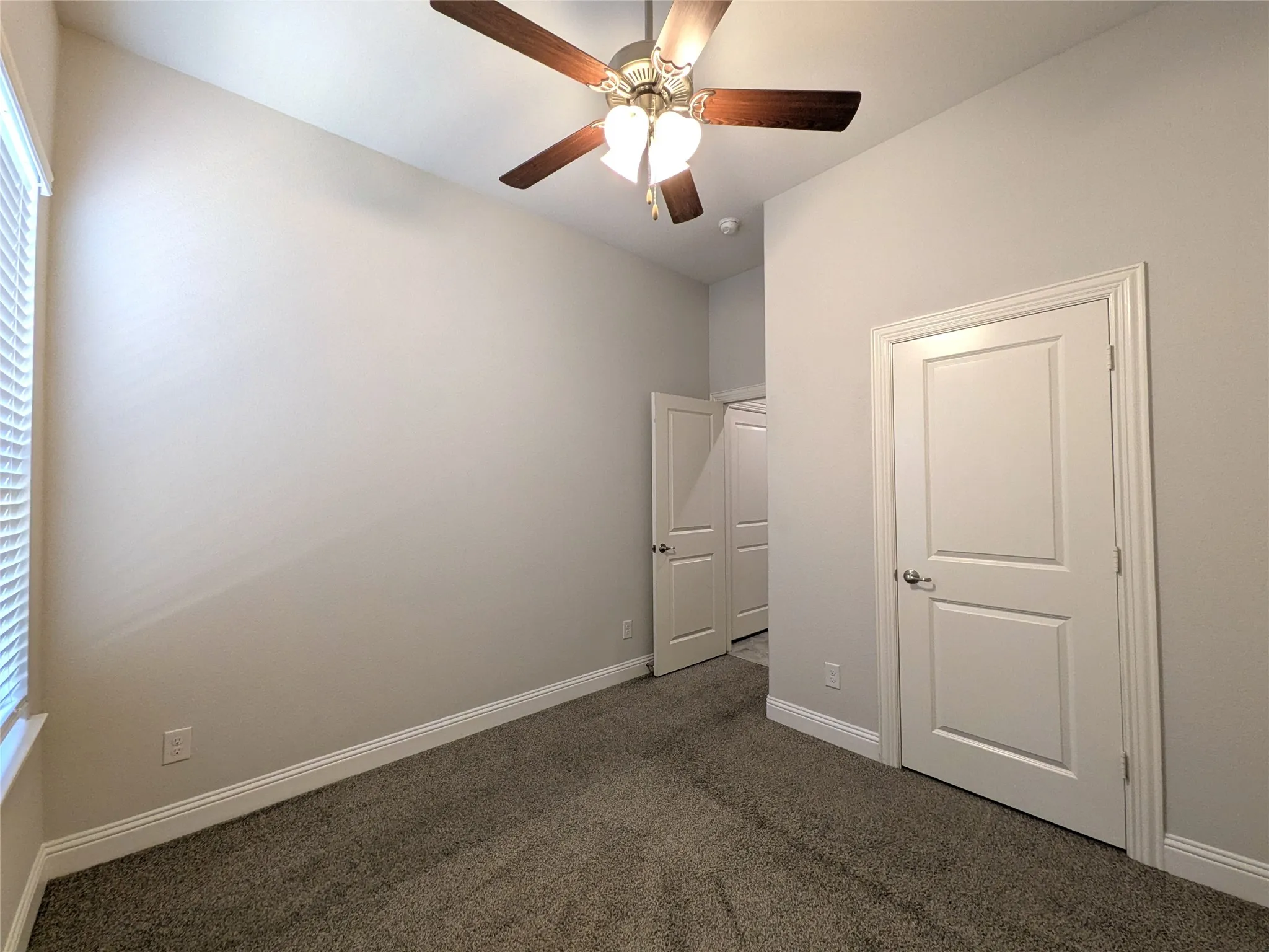 Carpeted room with a ceiling fan, vaulted ceiling, and white paneled doors