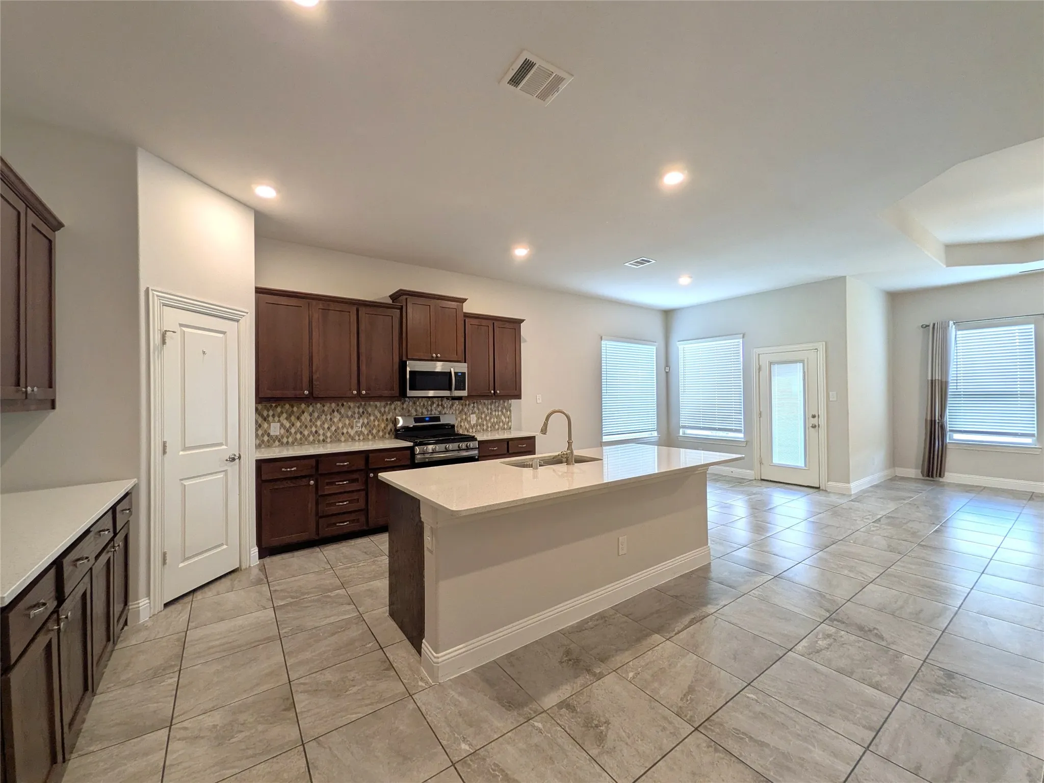 Spacious kitchen with a large island, wood-finish cabinetry, stainless steel appliances, and tile flooring