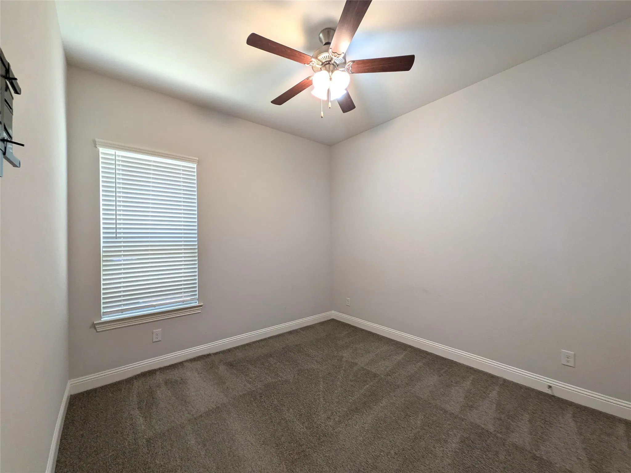 Carpeted room with a ceiling fan, window, and window blinds