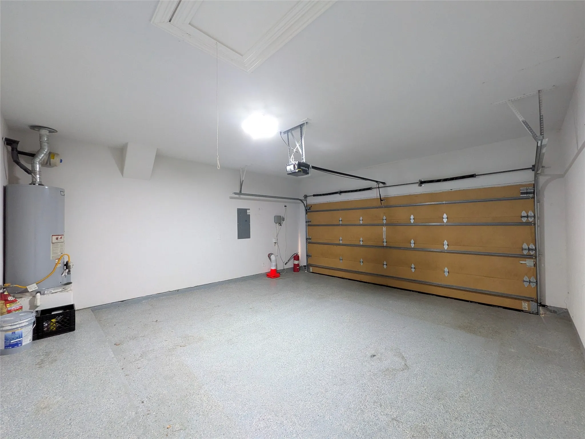 Spacious garage with light-colored flooring, overhead lighting, and a neutral-toned garage door