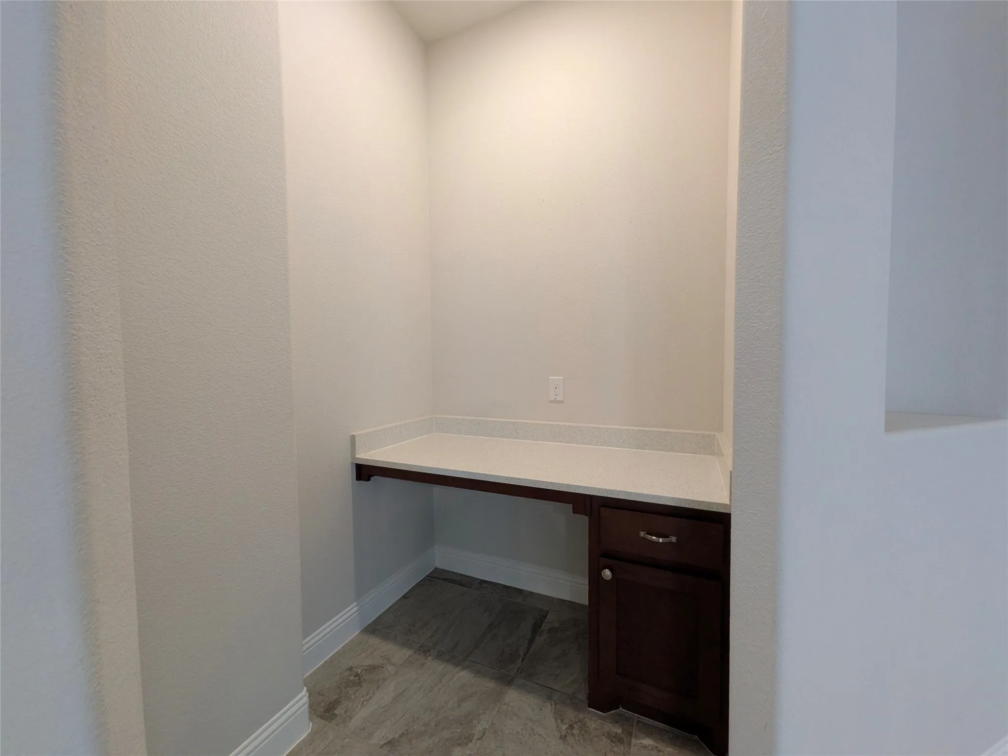 Built-in desk with a light-toned countertop, dark wood-finish cabinetry, and wood-finish flooring