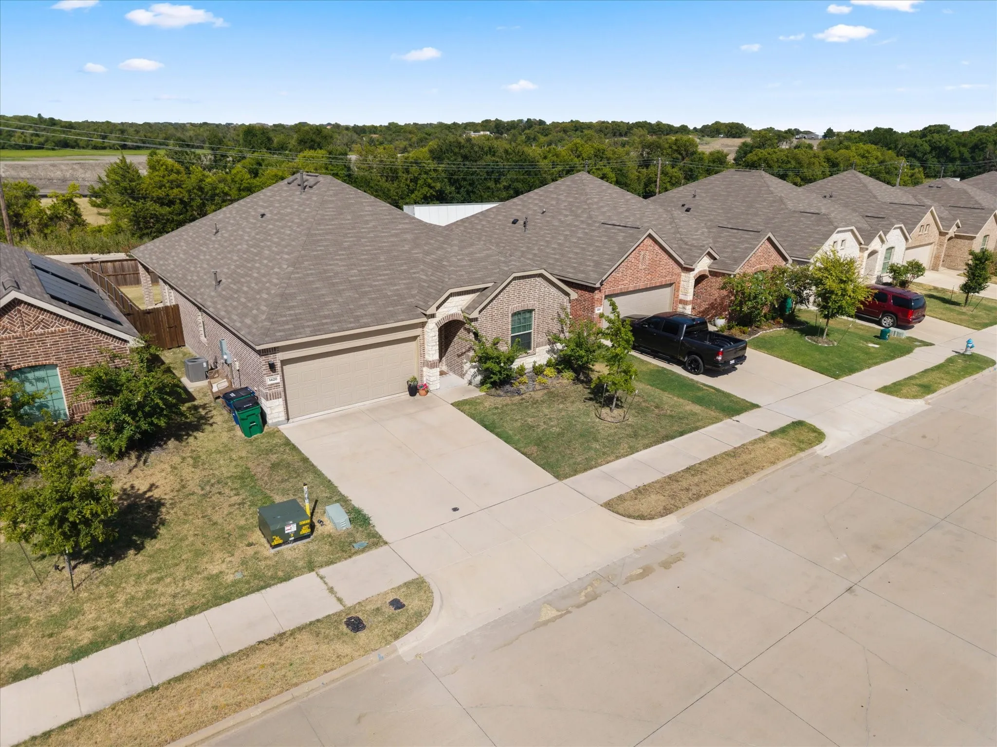 Brick and stone exterior with an attached garage, paved driveway, and mature landscaping