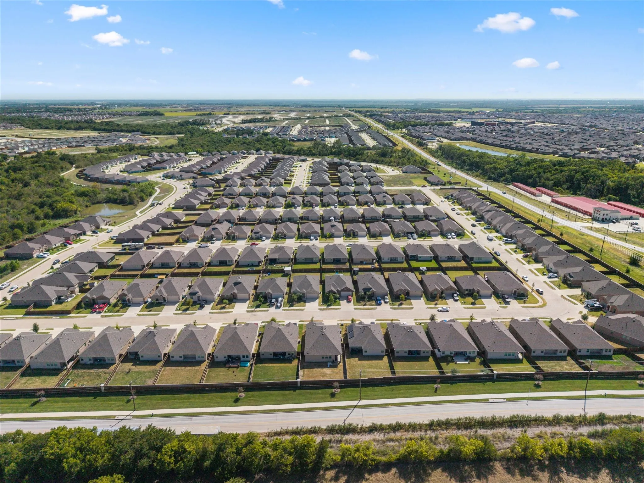 Expansive residential development featuring numerous single-story homes, structured street layouts, and a verdant perimeter