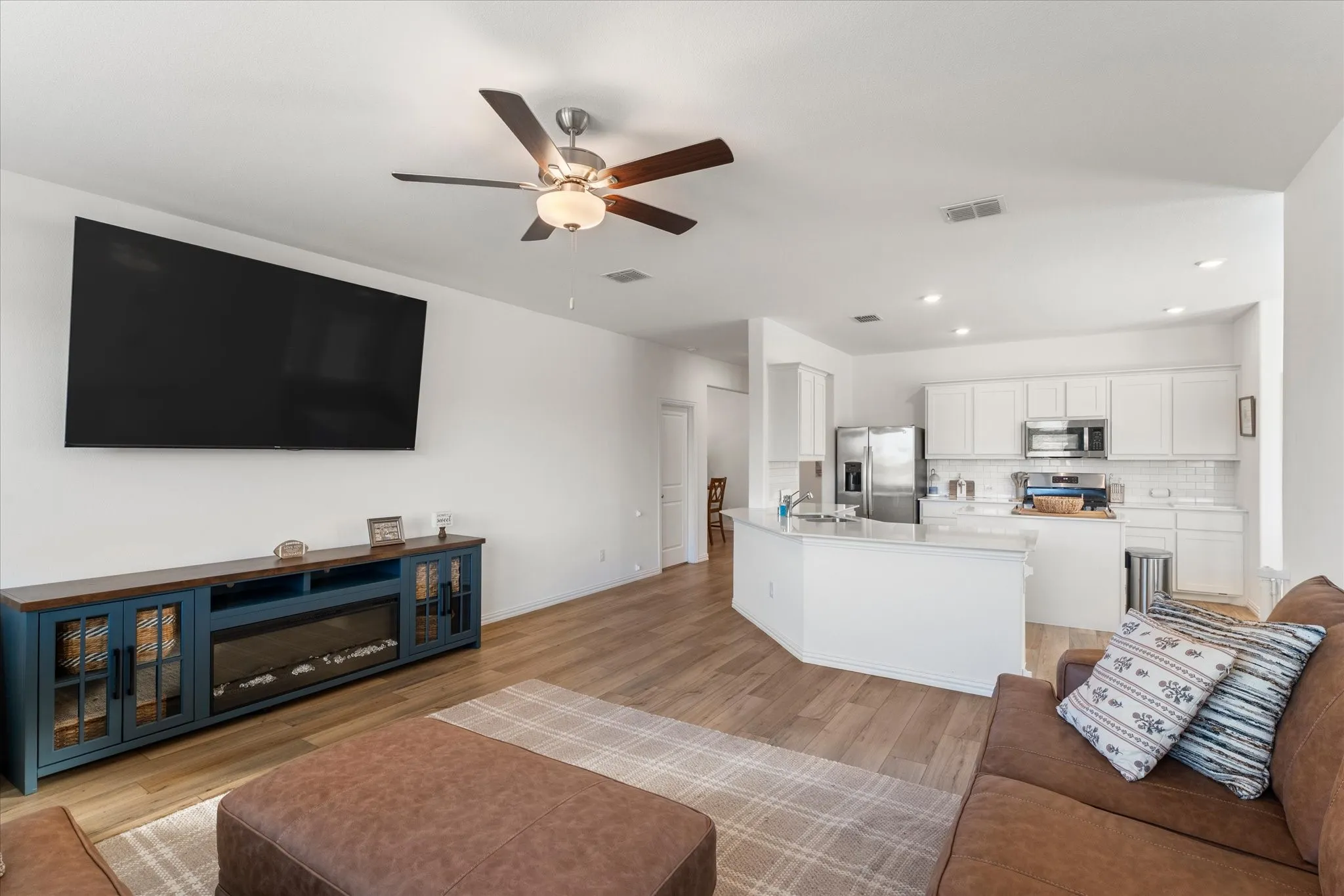 Open-concept living area with wood-finish flooring, recessed lighting, and a ceiling fan