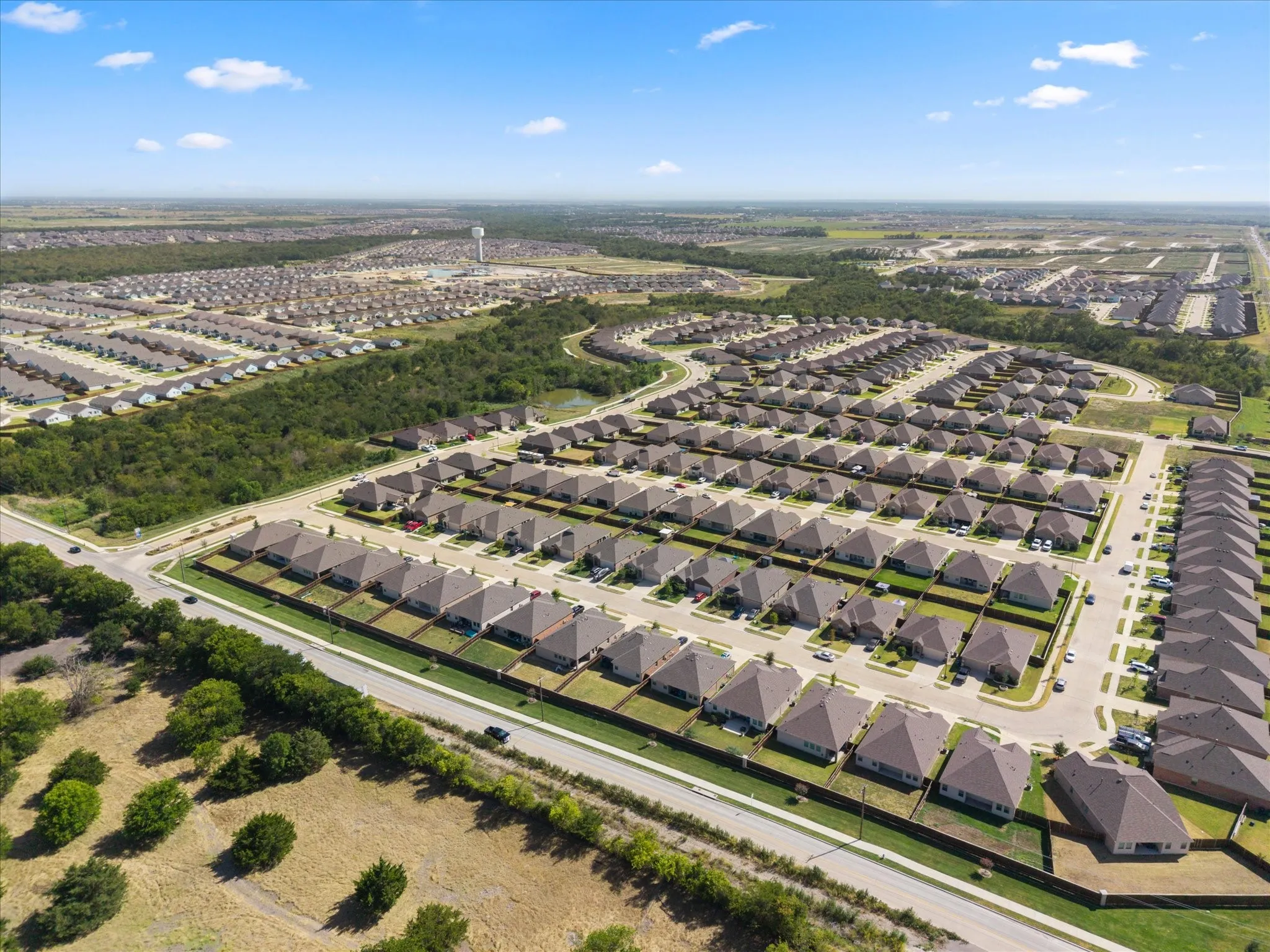 Expansive residential development featuring numerous single-story homes, uniform rooflines, and individual fenced yards
