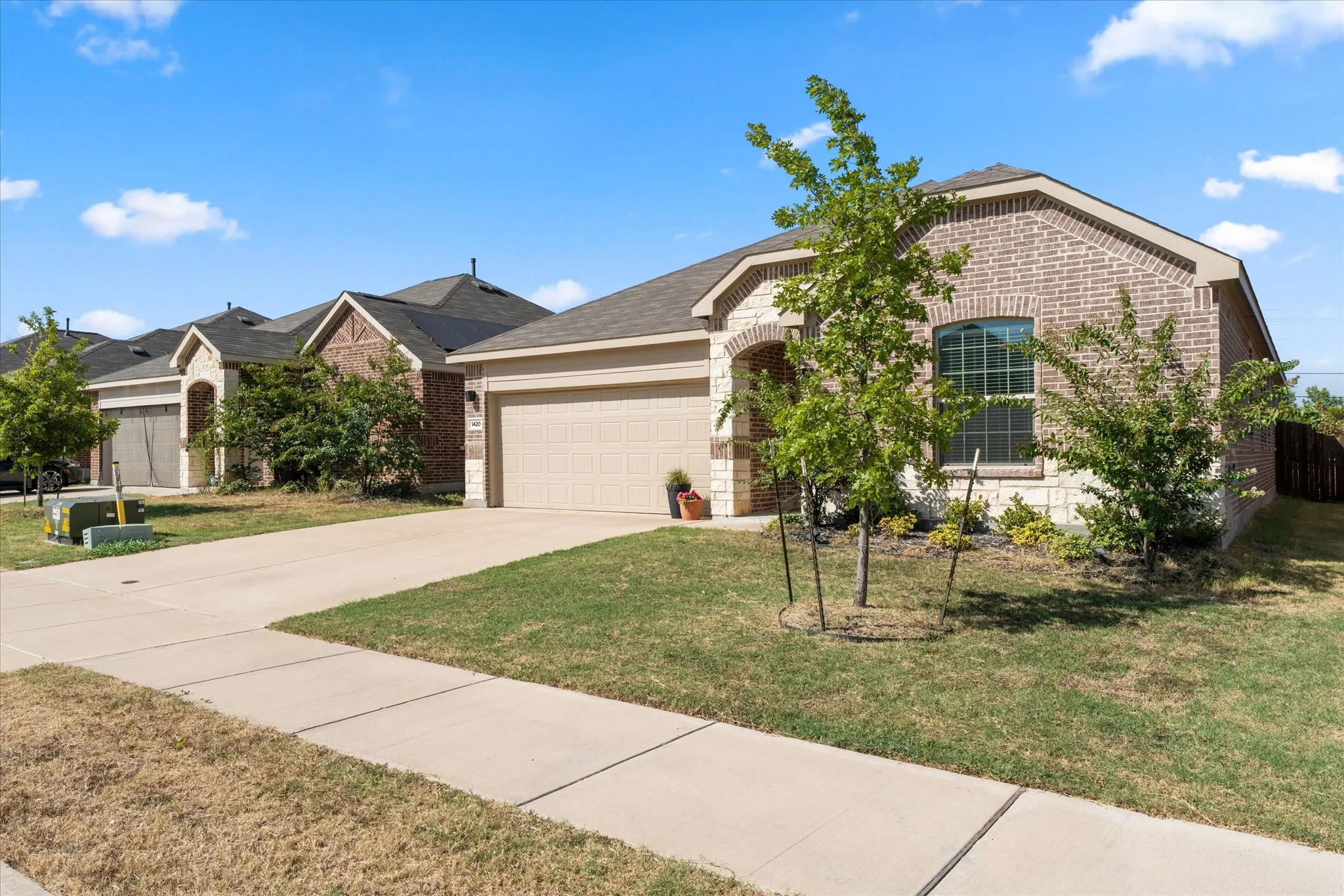 Brick and stone veneer exterior with an arched entry, an attached two-car garage, and a concrete driveway