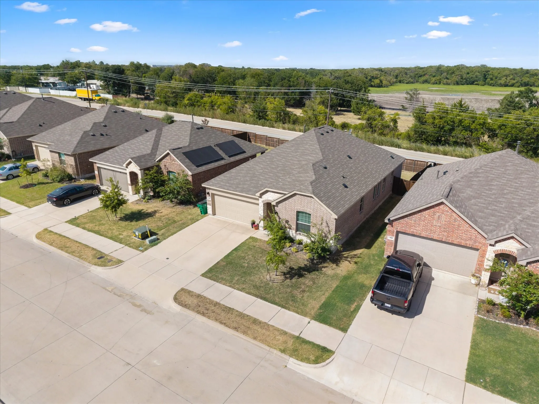 Brick exterior, attached garage, concrete driveway, front lawn, mature trees