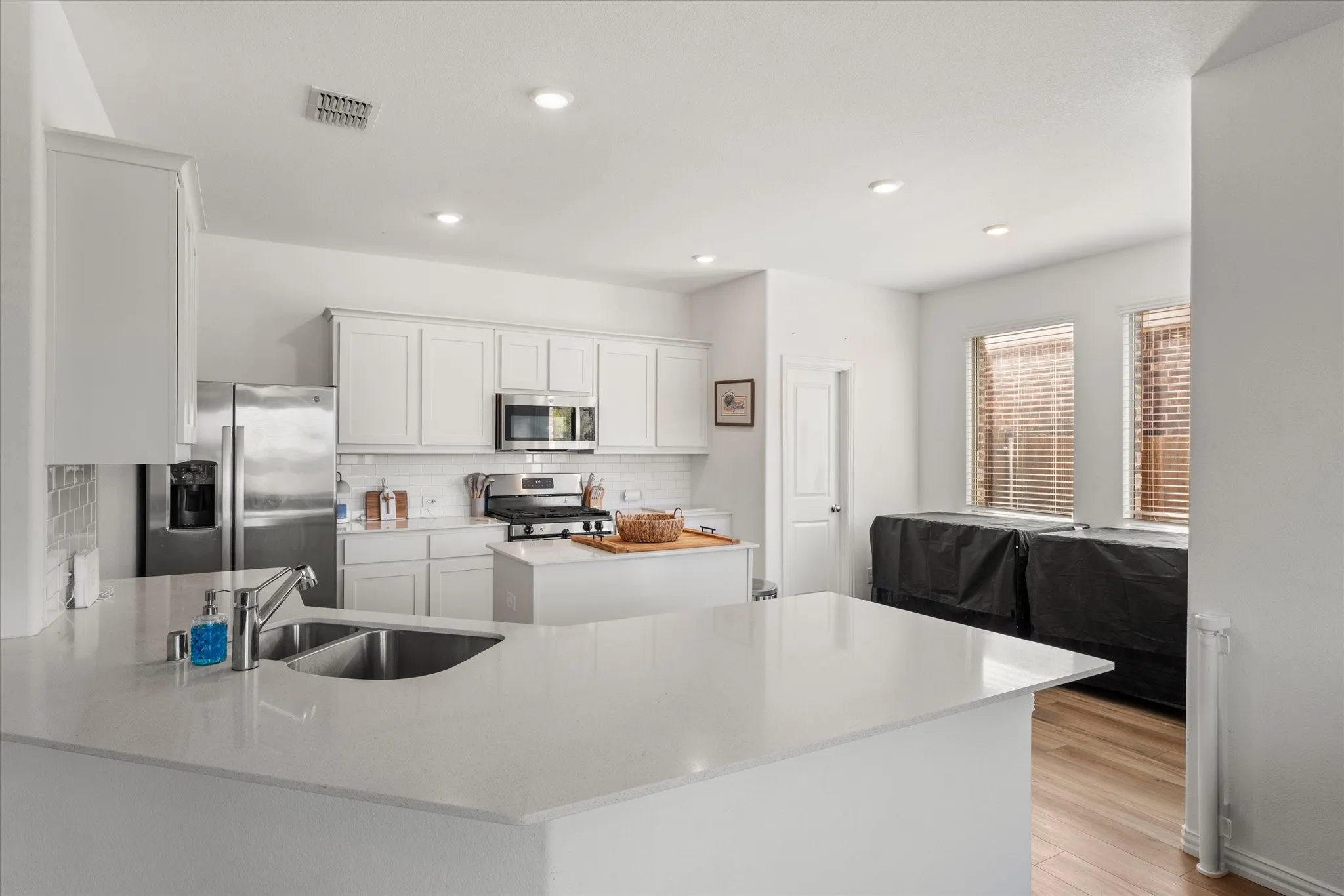 Kitchen featuring white cabinetry, stainless steel appliances, a center island, recessed lighting, and wood-finish flooring