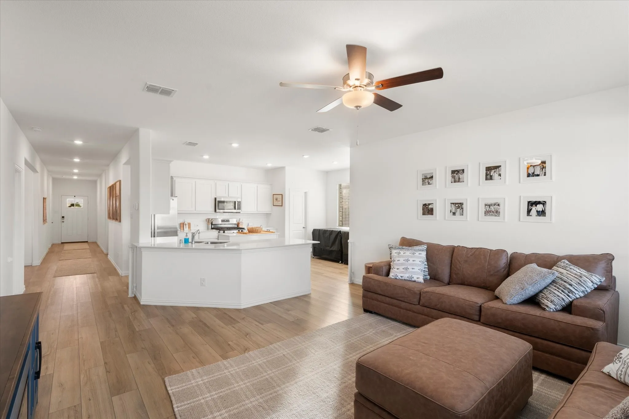 Open-concept living area featuring wood-finish flooring, recessed lighting, and a ceiling fan