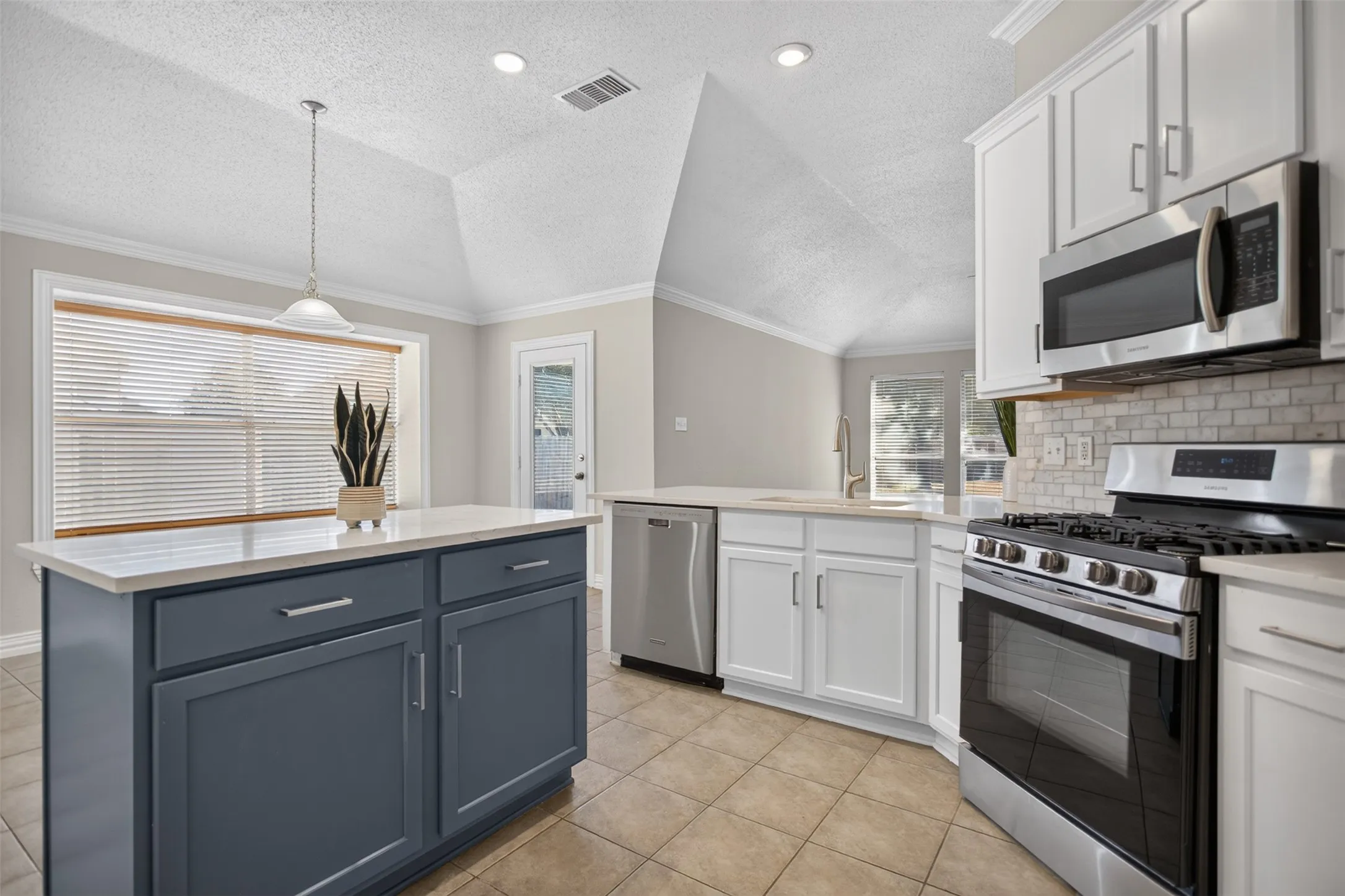Stainless steel appliances, gas range and island in the kitchen