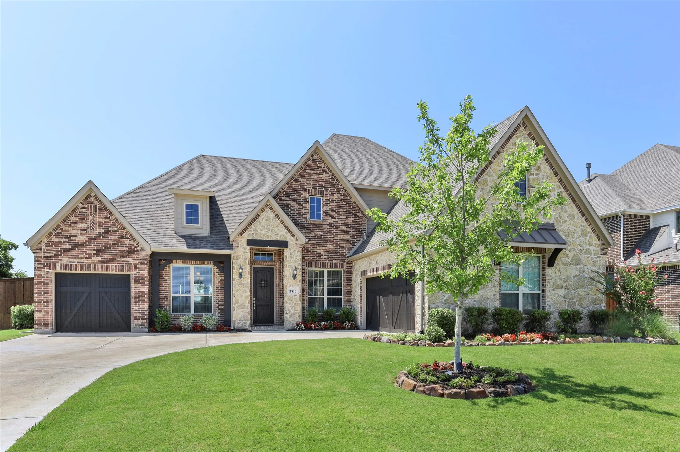 Front of home with landscaped yard, and three car garage