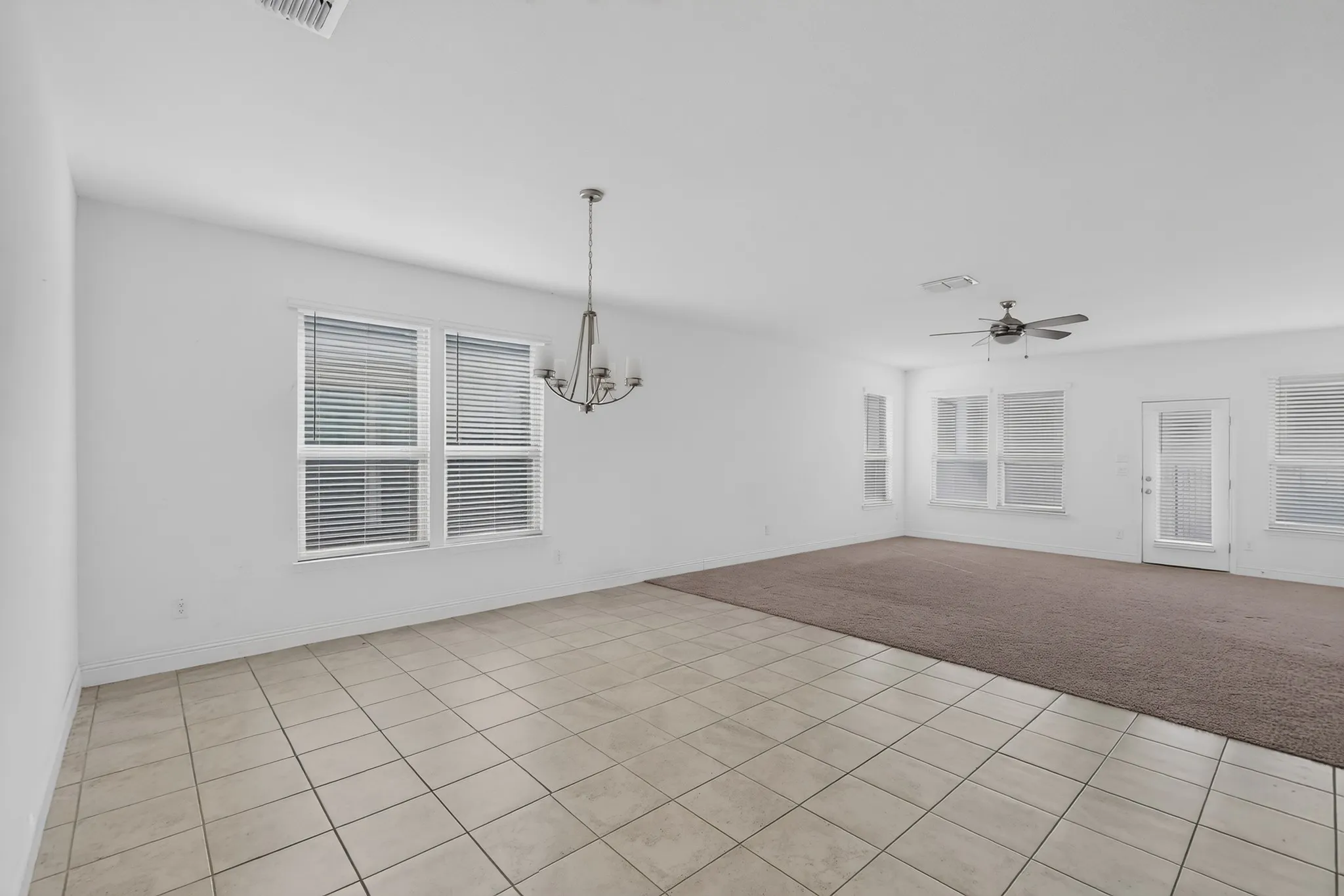 Spacious room with a neutral color palette, tile flooring, and carpeted area