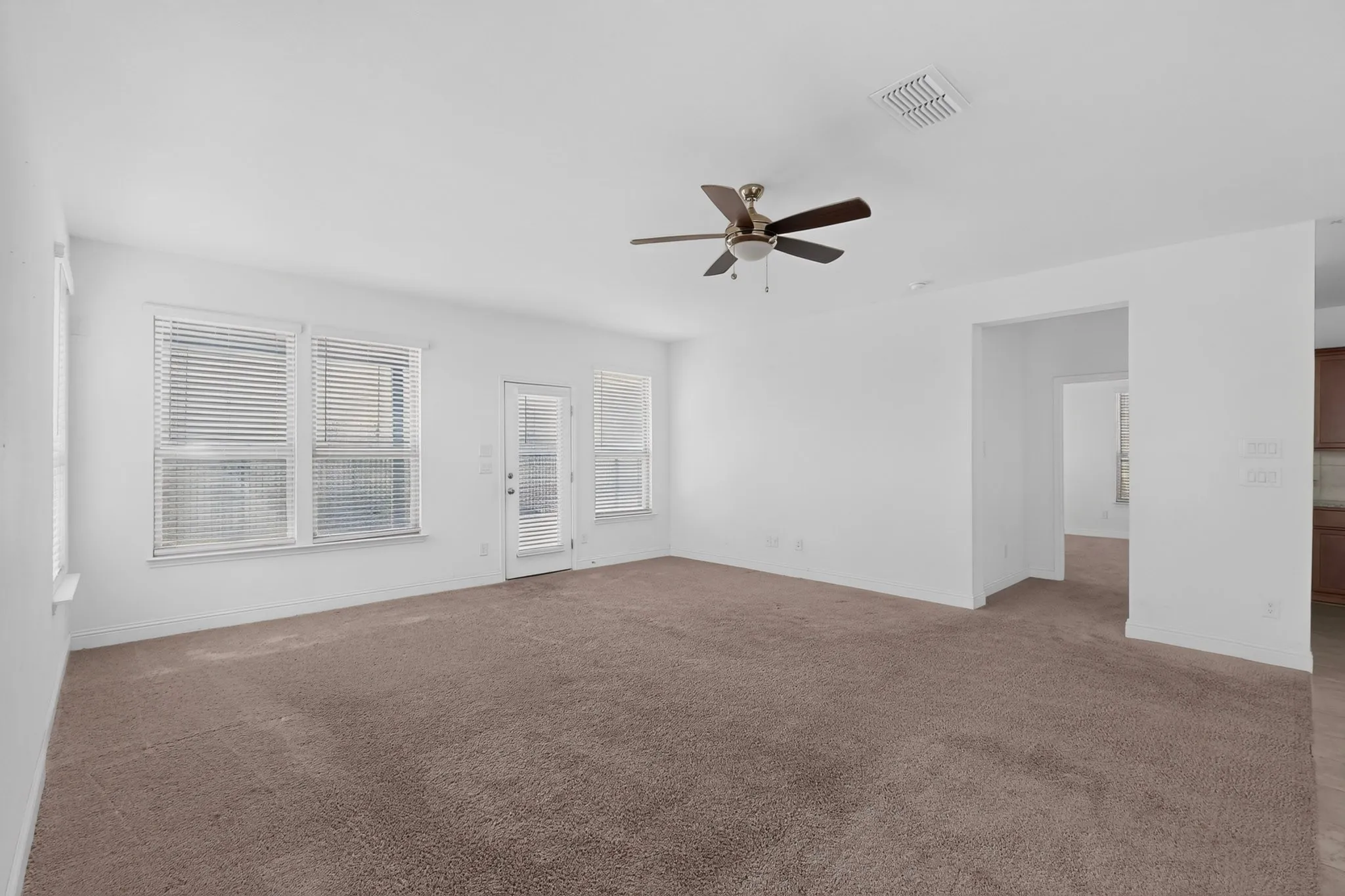 Expansive room featuring multiple windows, a ceiling fan, and carpeted flooring