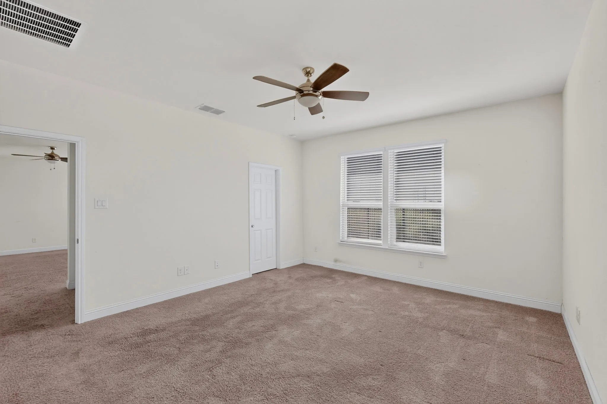 Spacious room with carpet flooring, a ceiling fan, and white window blinds
