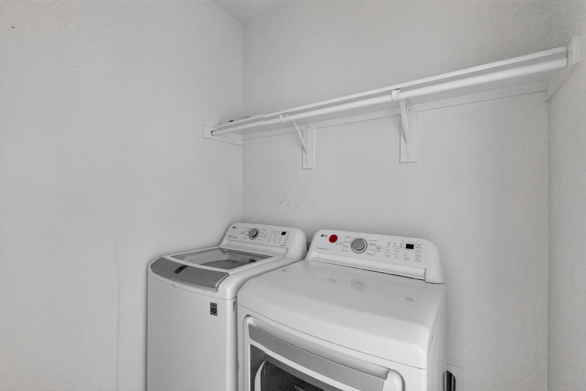 Laundry area featuring a top-load washing machine, front-load dryer, and an integrated clothes hanging rod