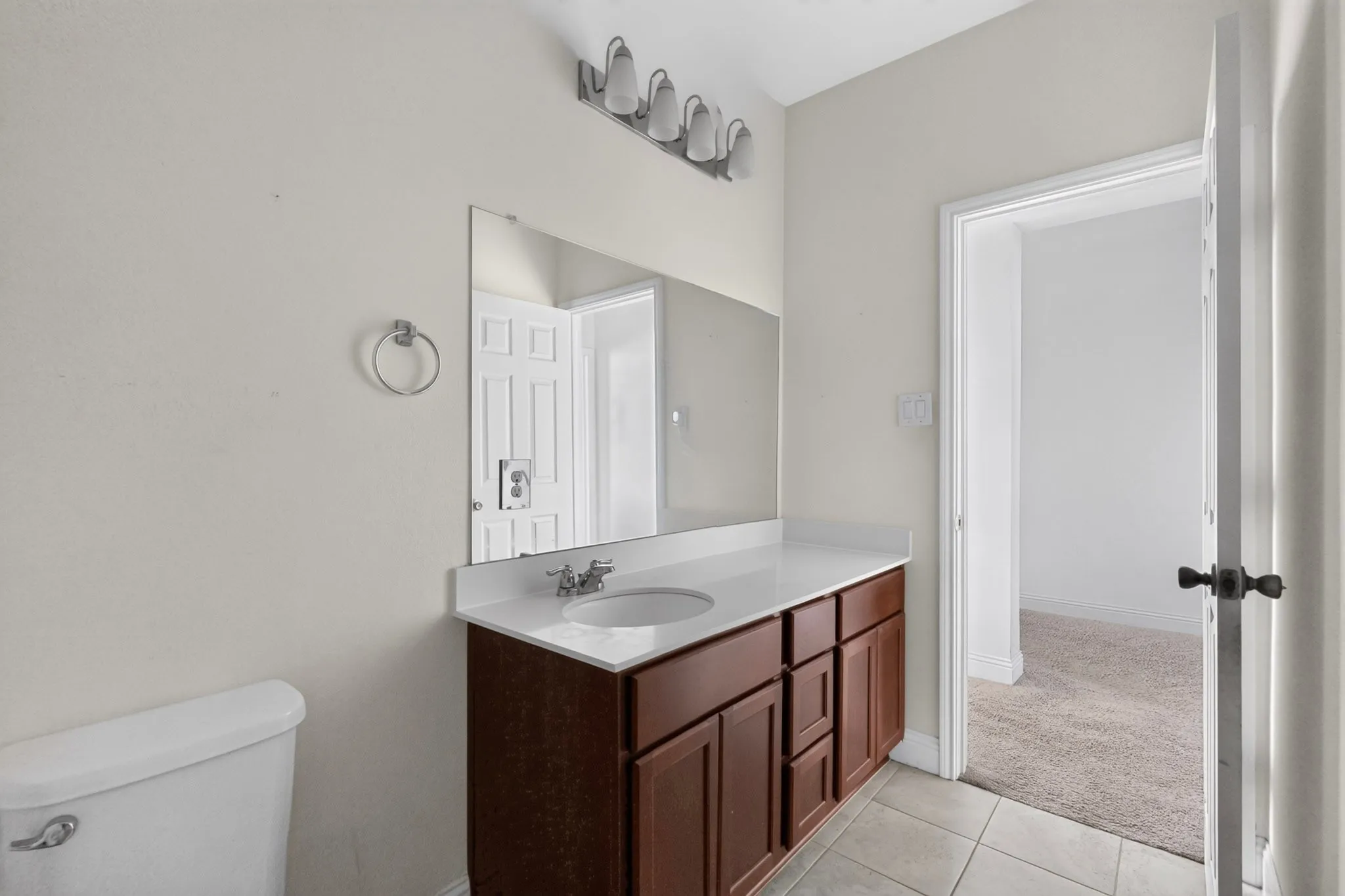 Bathroom featuring a wood-finish vanity with an integrated sink, a large wall mirror, and tiled flooring