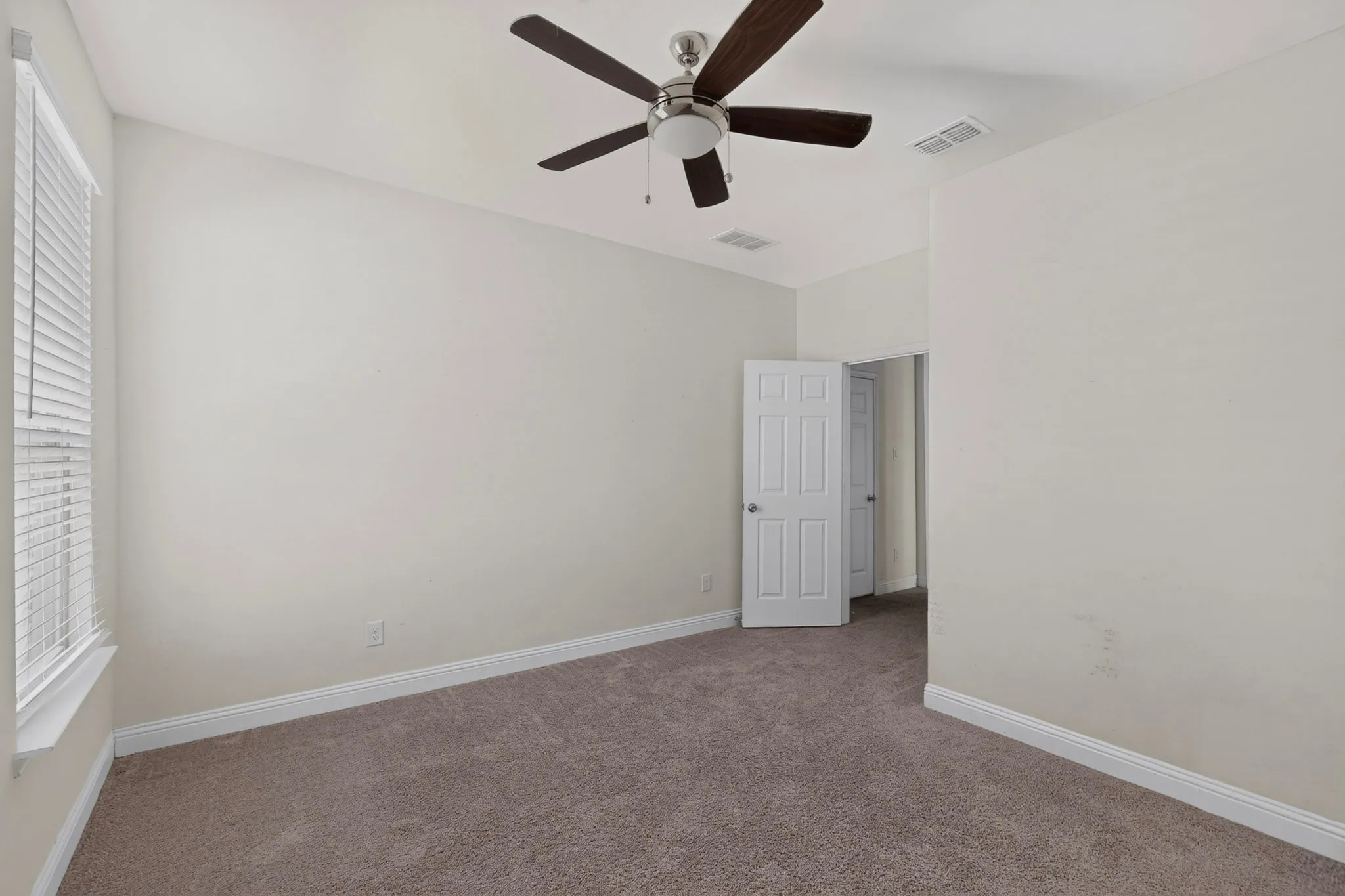 Carpeted room featuring a ceiling fan with integrated lighting, white window blinds, and paneled doors