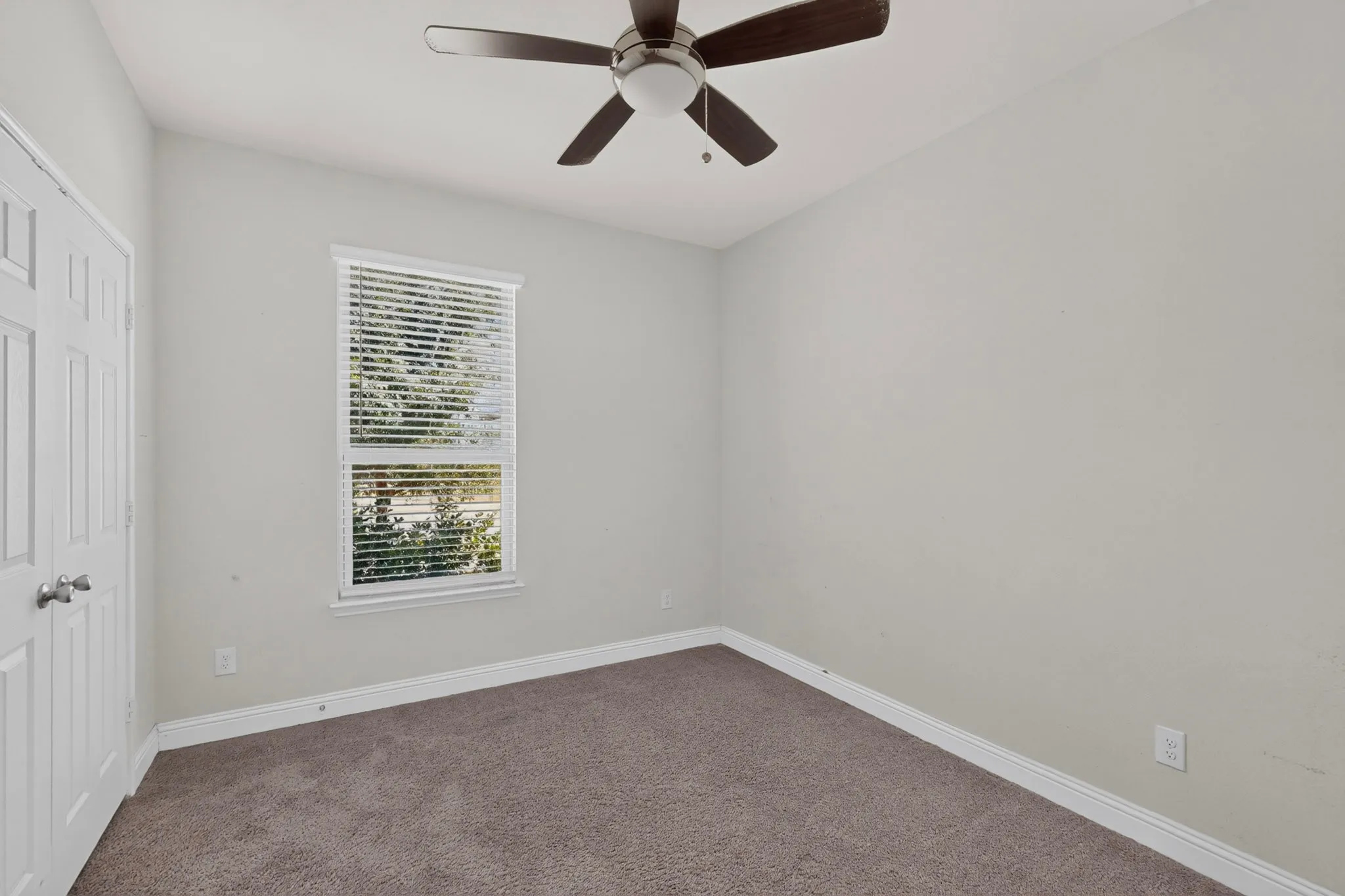 Recessed window with blinds, ceiling fan with light fixture, neutral wall color, white trim, and carpeted flooring