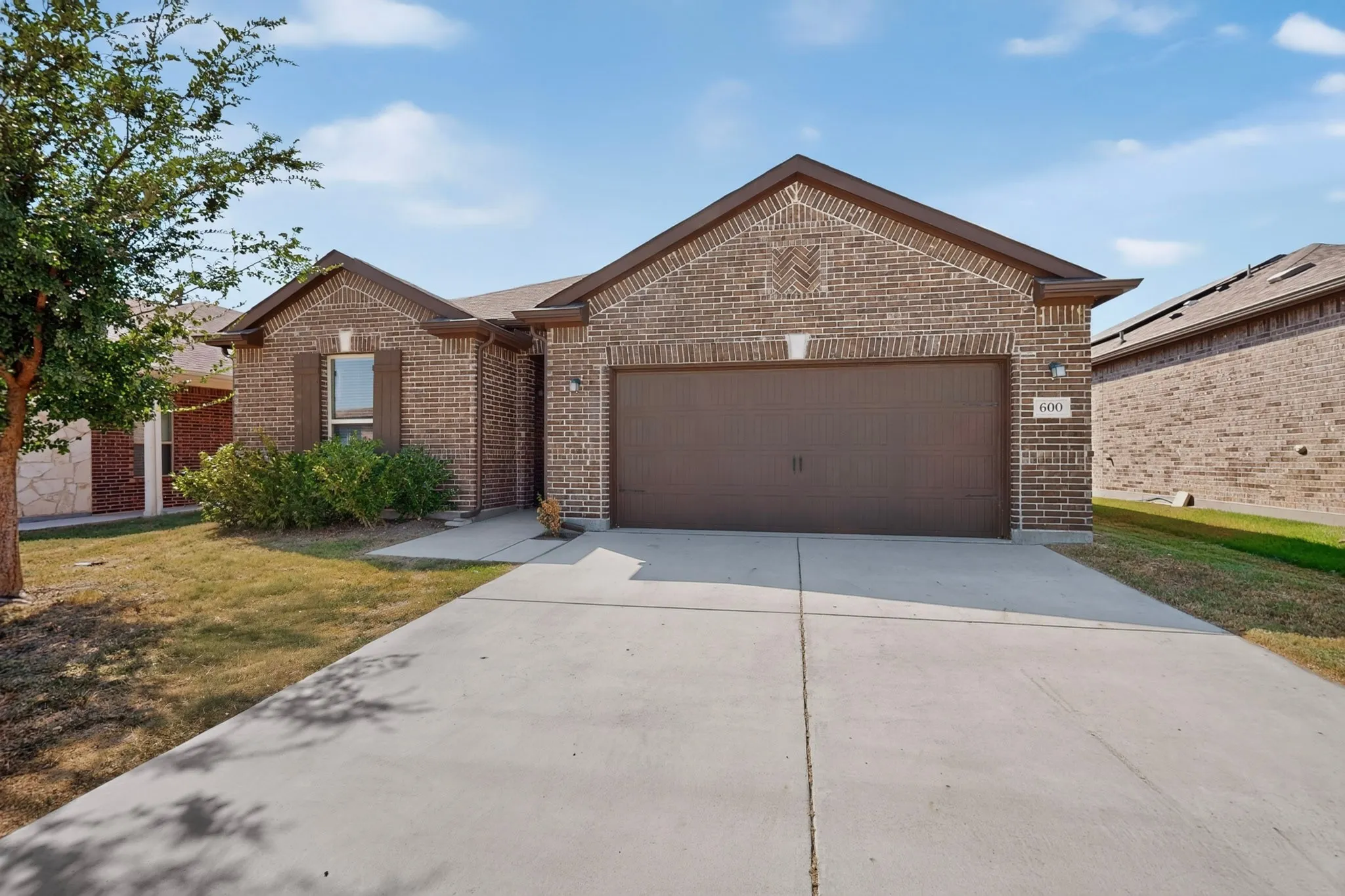 Brick exterior featuring a two-car garage and concrete driveway