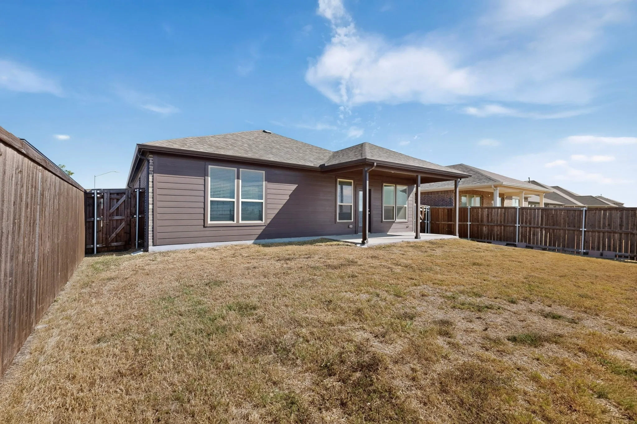 Fenced backyard featuring a covered patio, horizontal siding, and multiple windows