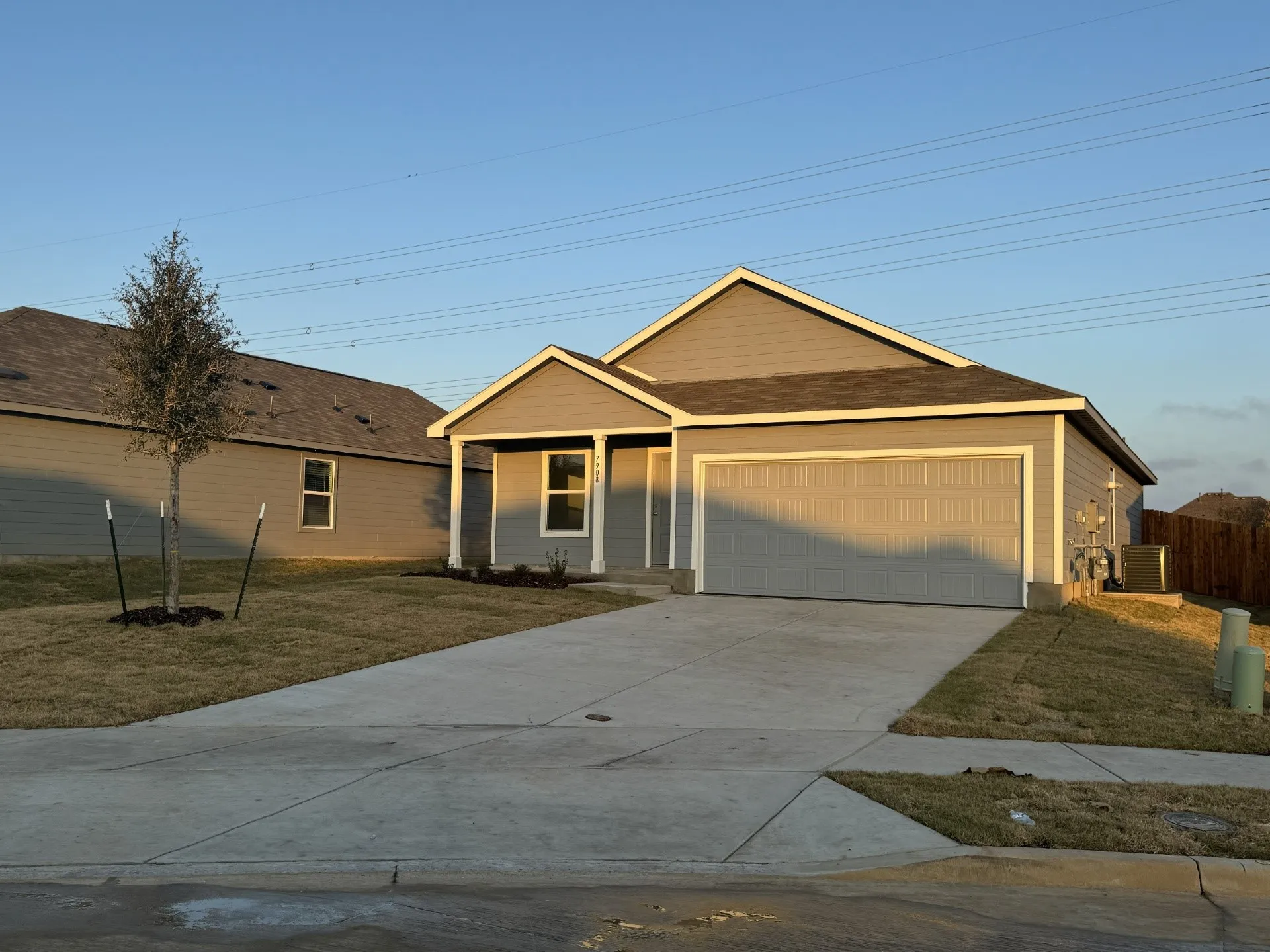 Single-story residence featuring a two-car garage, grey siding exterior, a front porch, and a concrete driveway
