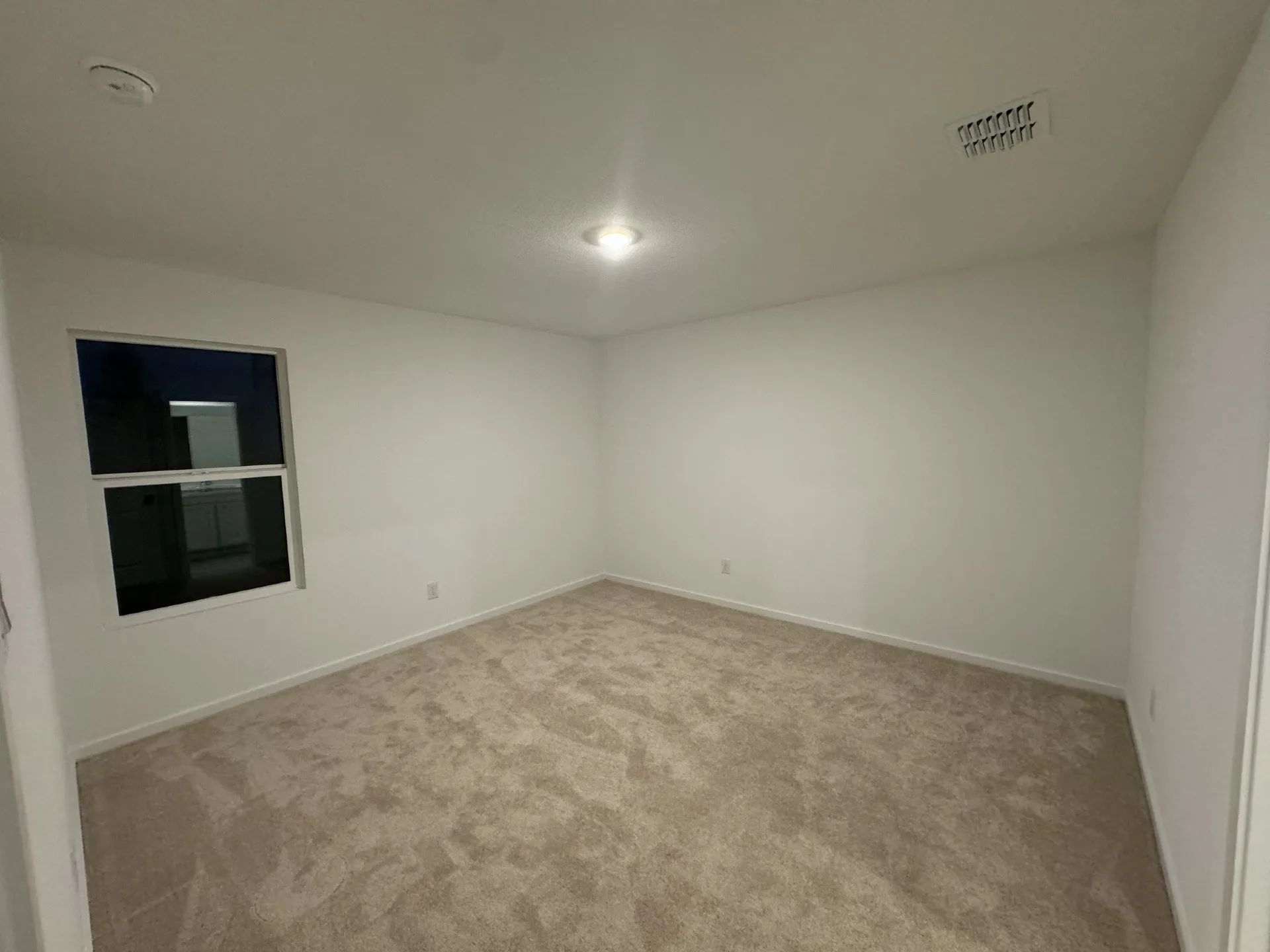 Recessed ceiling light, neutral-toned carpeting, white walls, and a window