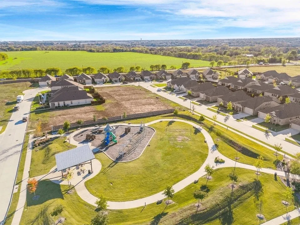 Expansive community green space with meandering pathways, a children's play area, and a shaded picnic structure