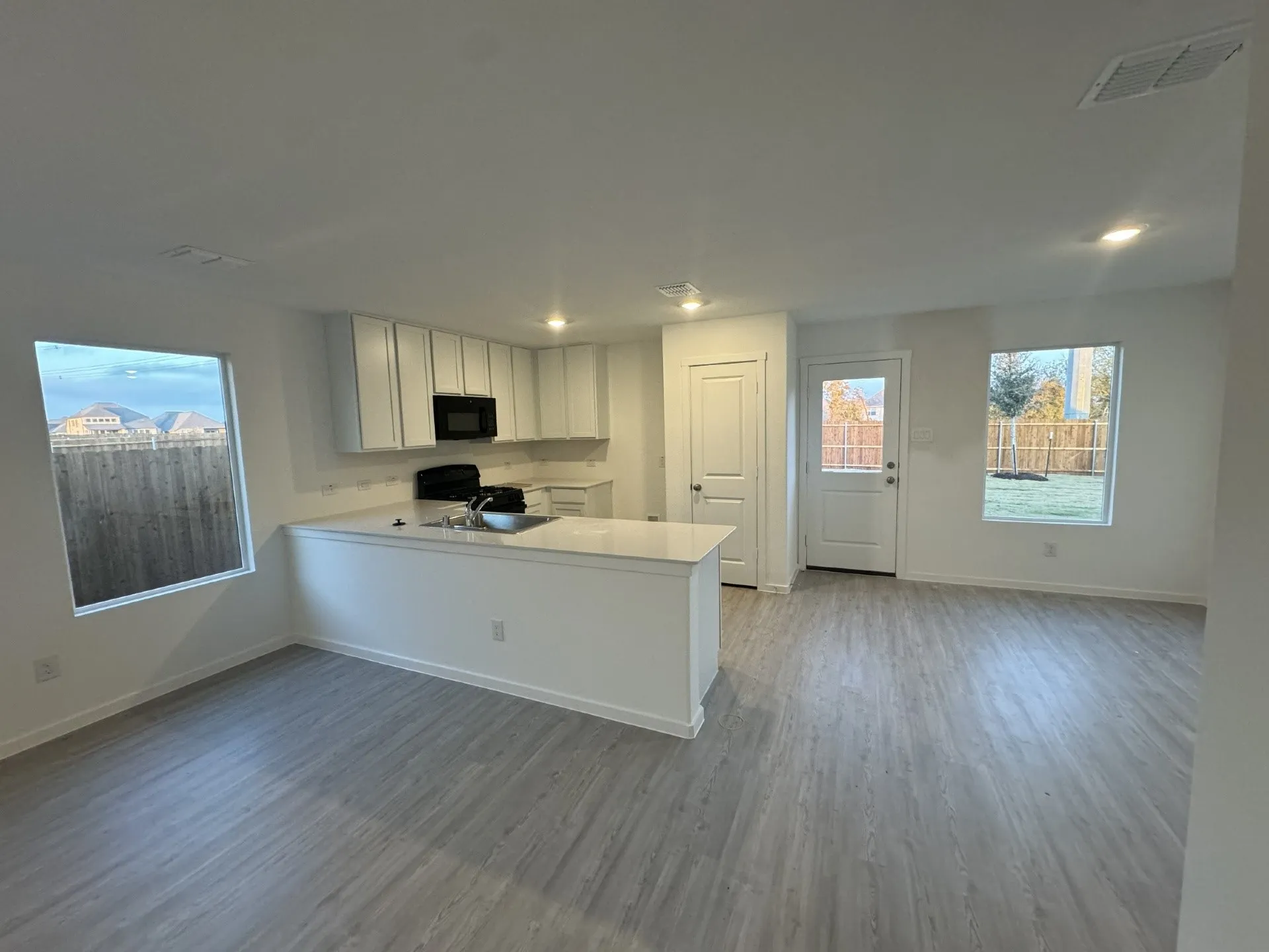 Open-concept living area with wood-finish flooring, recessed lighting, and ample natural light