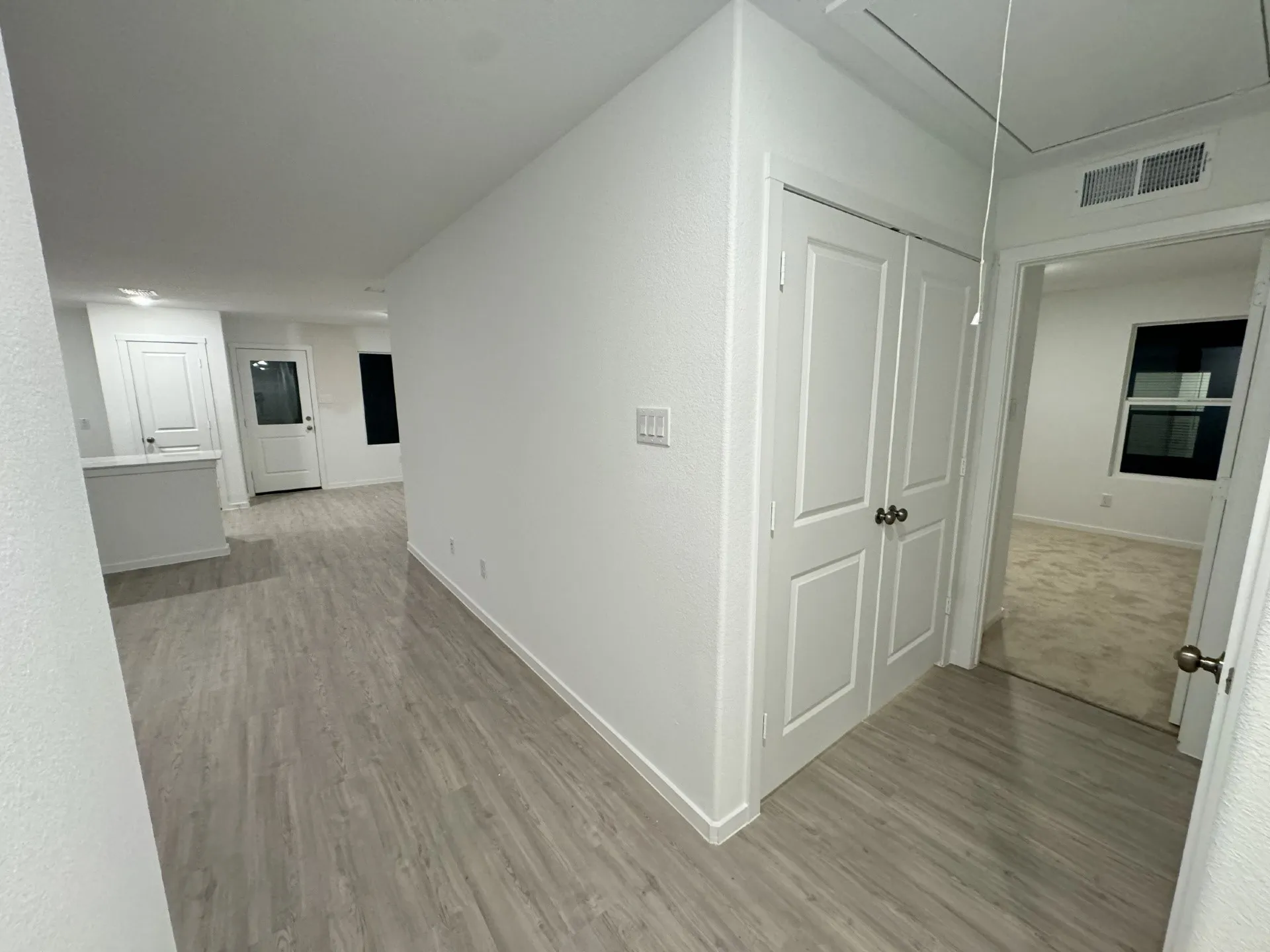 Wood-finish flooring extending into the living area, white paneled doors, and a built-in kitchen peninsula