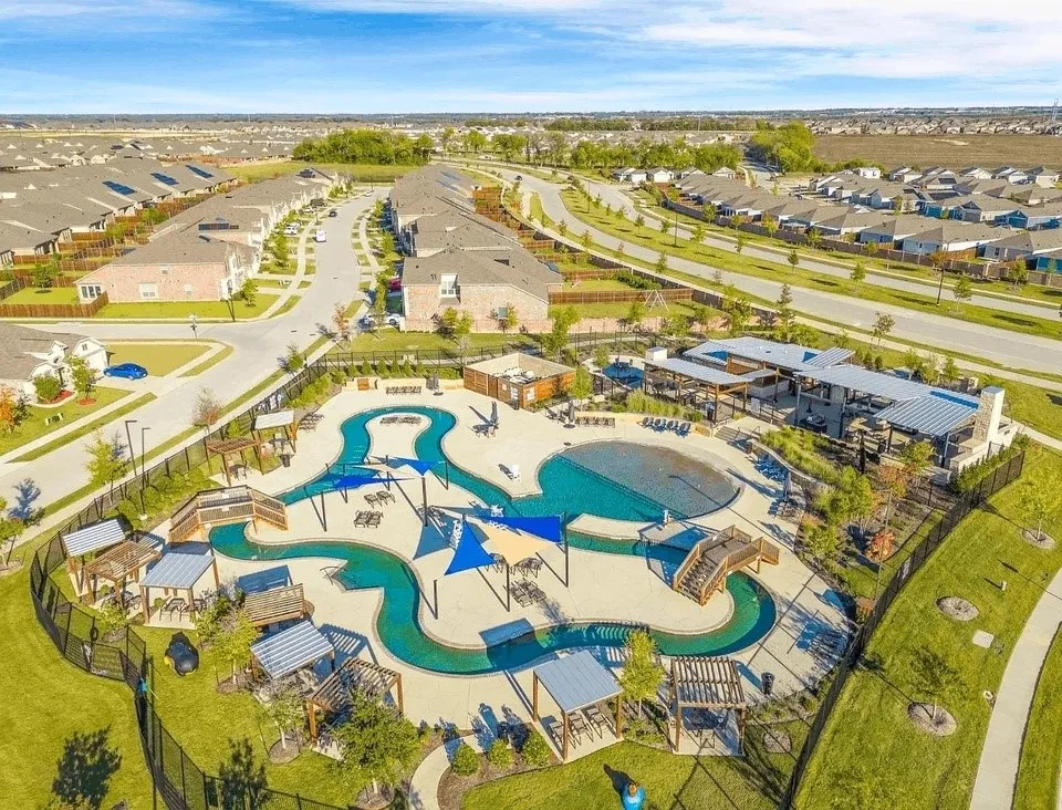 Resort-style pool area featuring a winding river, integrated lounge seating, and shaded pergola structures