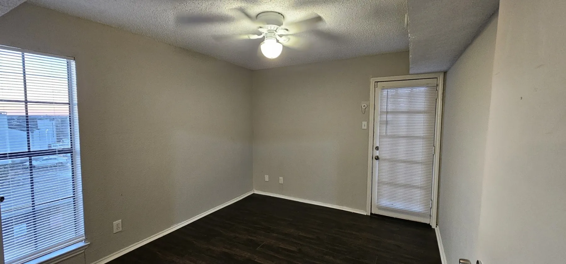 Wood-finish flooring with neutral wall tones, a ceiling fan with integrated lighting, and a glass-paneled exterior door